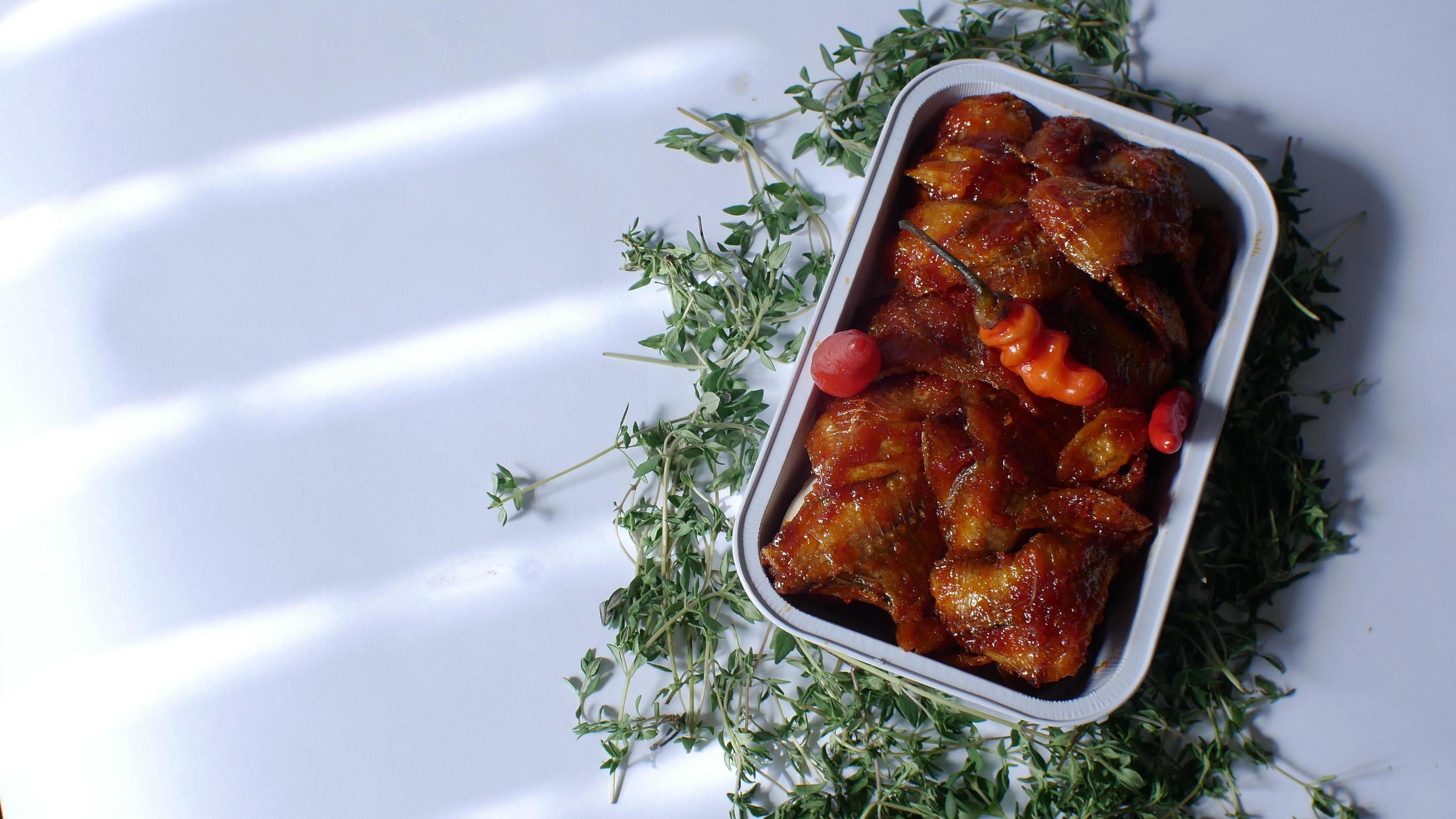 salted fish with spicy sweet and sour seasoning Indonesian food served simply in an aluminum place with white background Stock Free