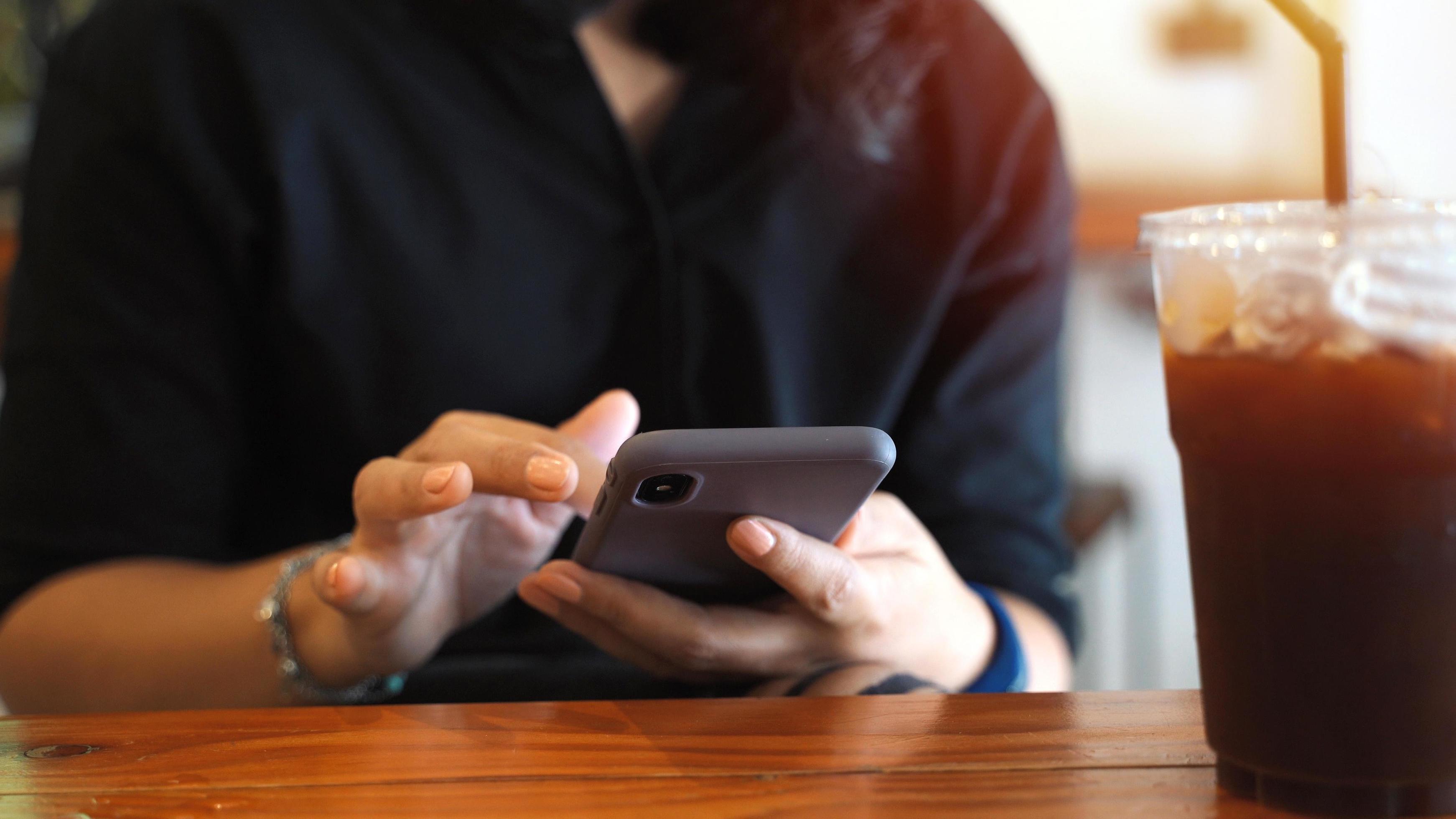 Young customer asian woman using smartphone while drinking iced coffee in the cafe, lifestyle and technology concept Stock Free