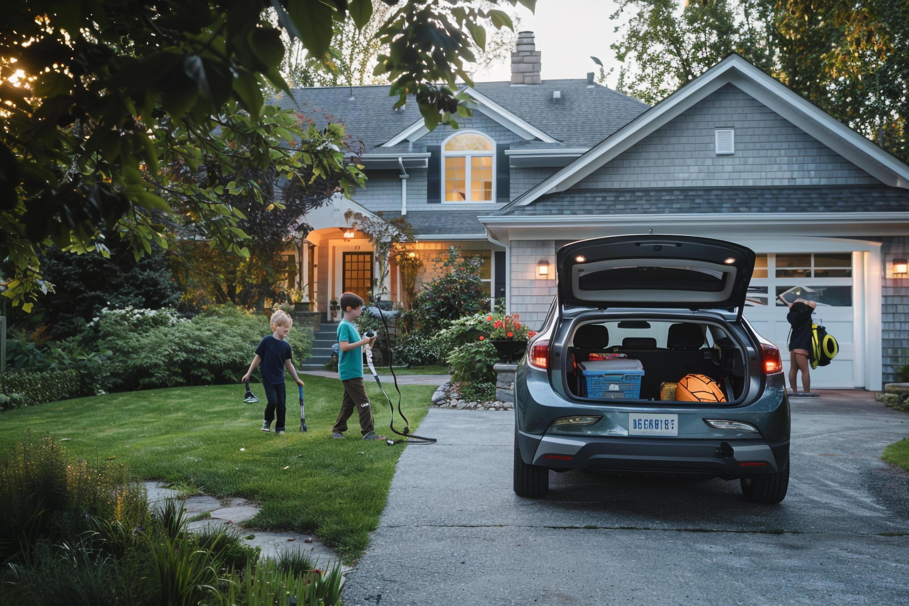 Hybrid Car in Suburban Driveway with Family and Sports Equipment Background in Nature Stock Free