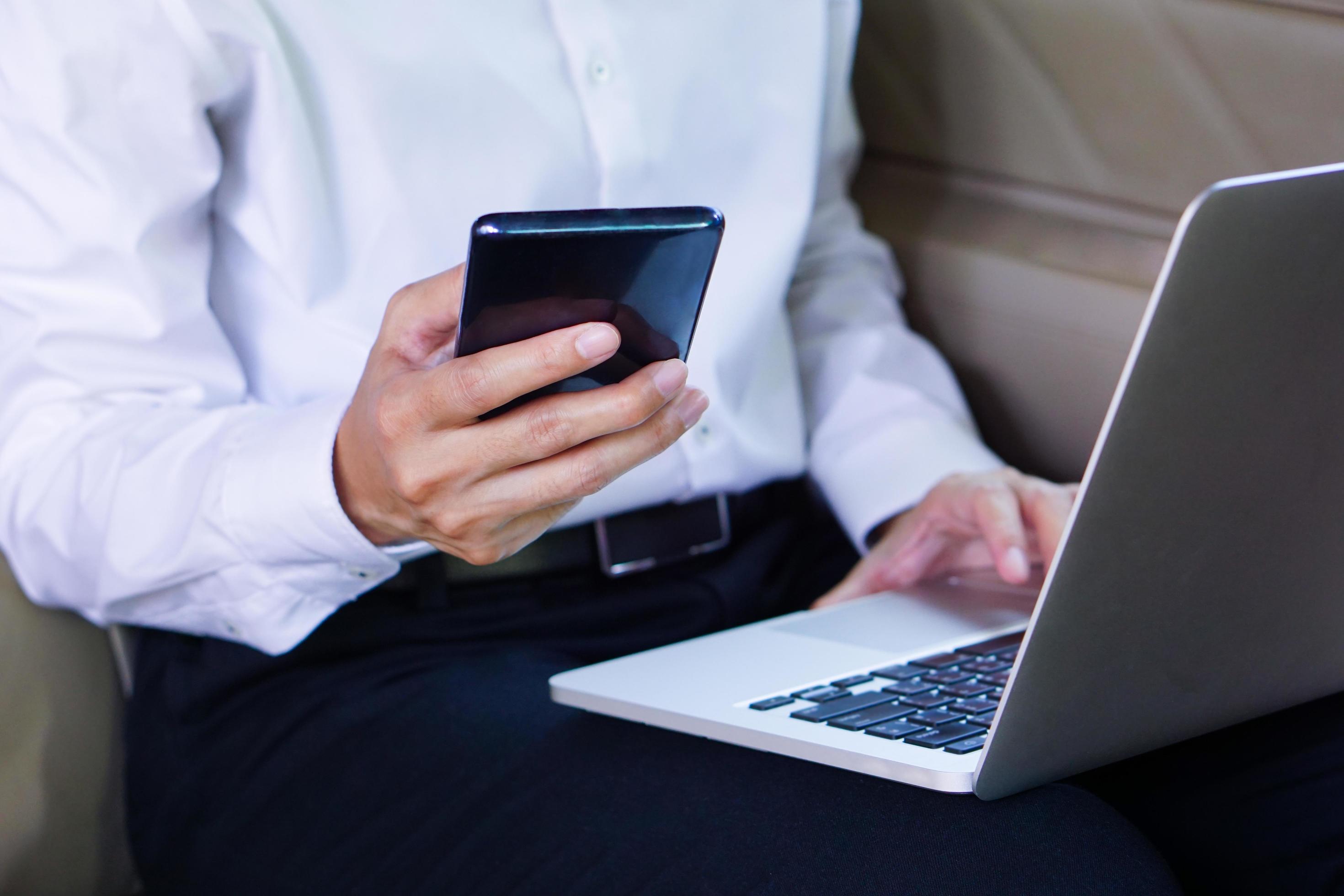 Businessman working on laptop and mobile phone while sitting in car. Lifestyle concept. Stock Free