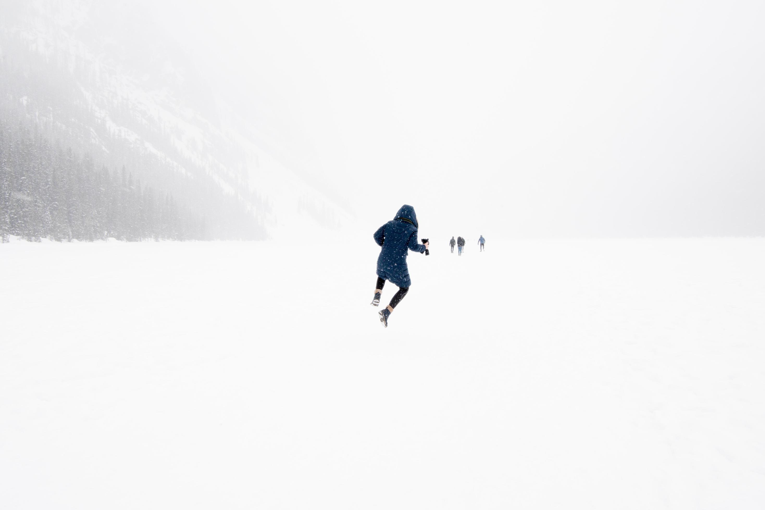 Young person jumping in the air in a winter landscape with snow. Frozen Lake Louise, Banff National Park, Canada Stock Free