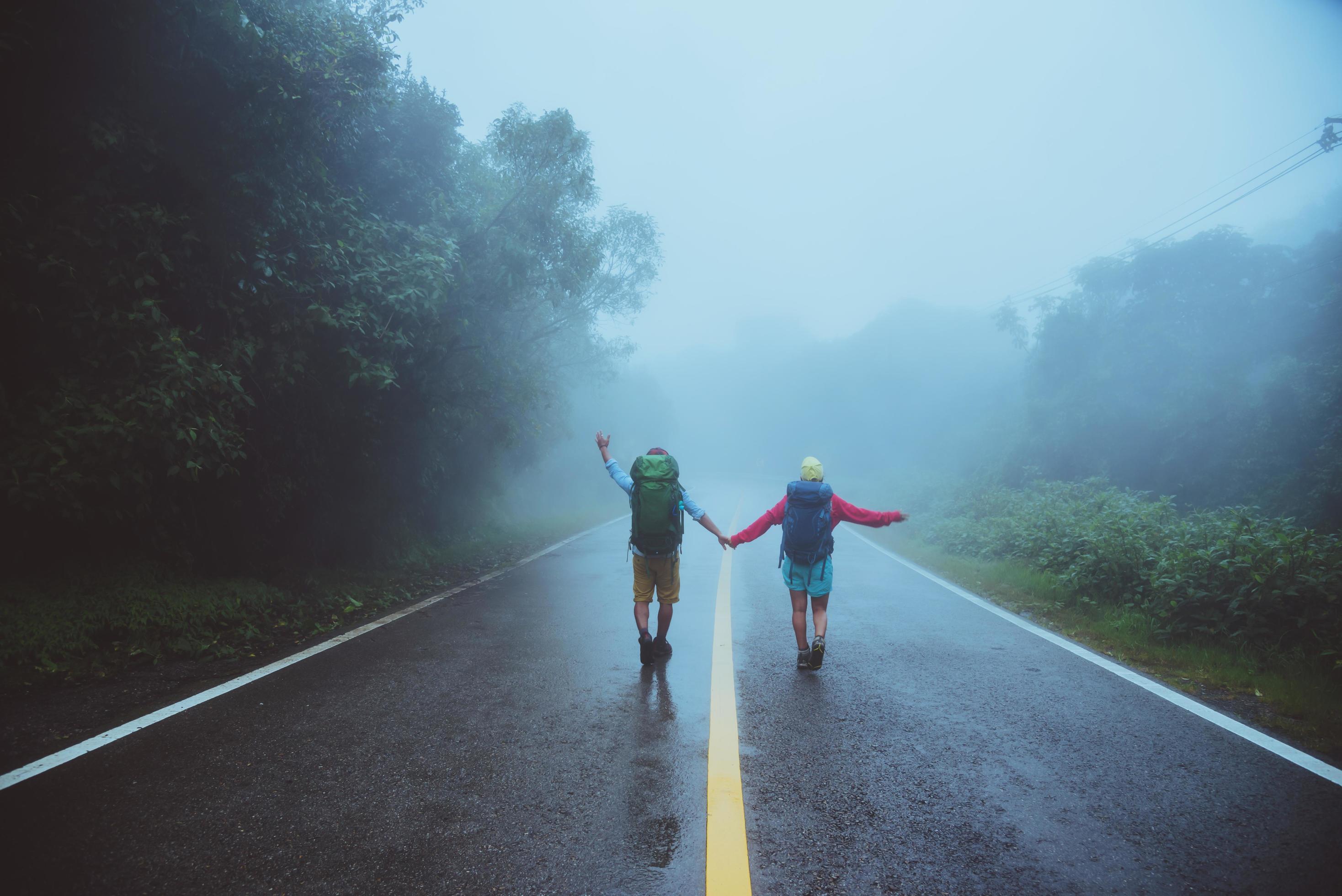 Lover asian man and asian women travel nature. Walk on the road route. traveling nature happily. Amid the mist rainy. Stock Free