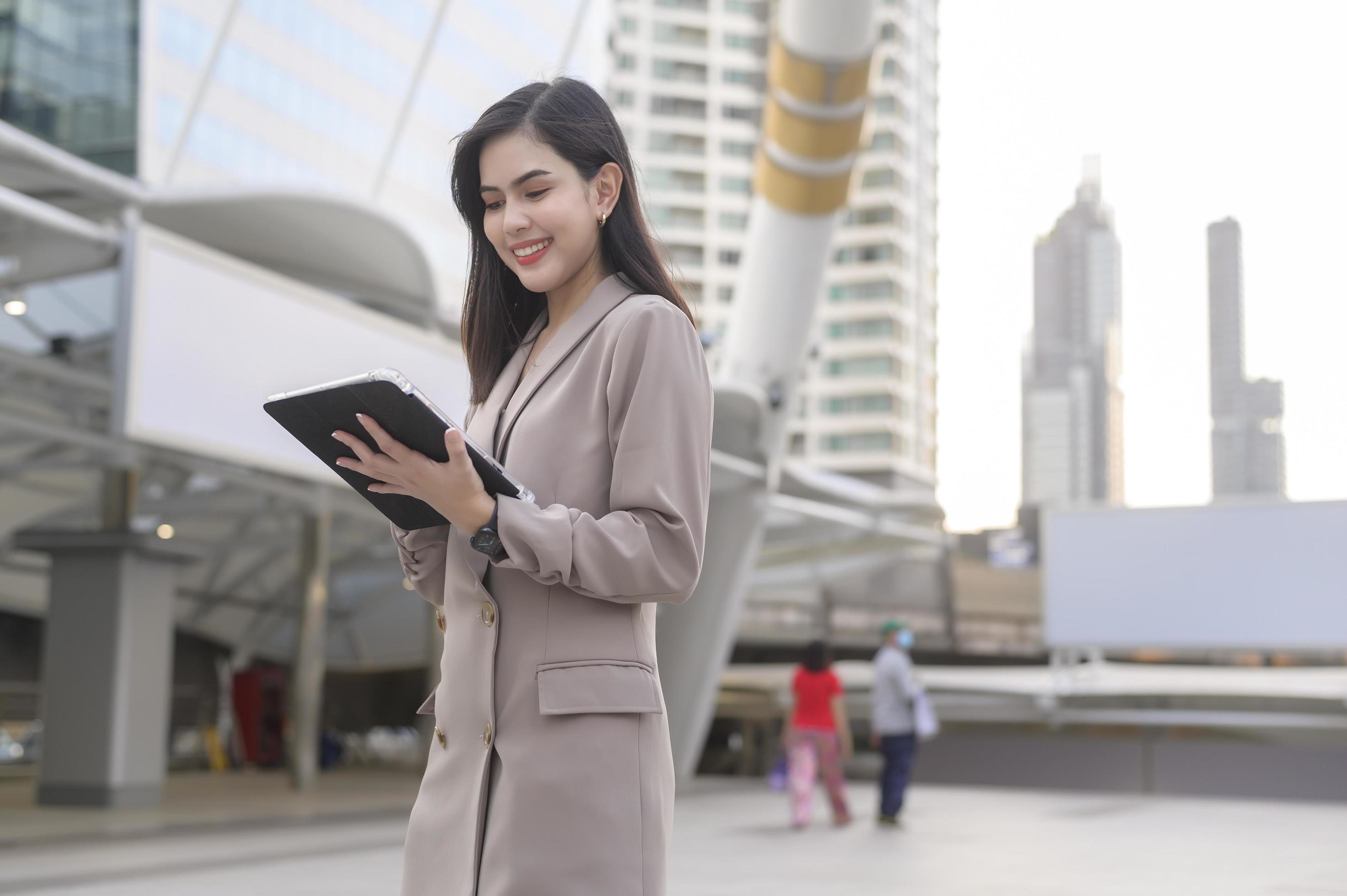 A young beautiful businesswoman is using tablet in Modern city , business technology , city lifestyle concept Stock Free