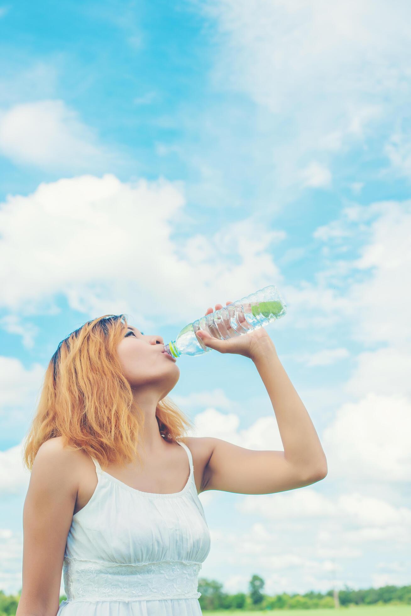 Women lifestyle concept young beautiful woman with white dress drinking water at summer green park. Stock Free