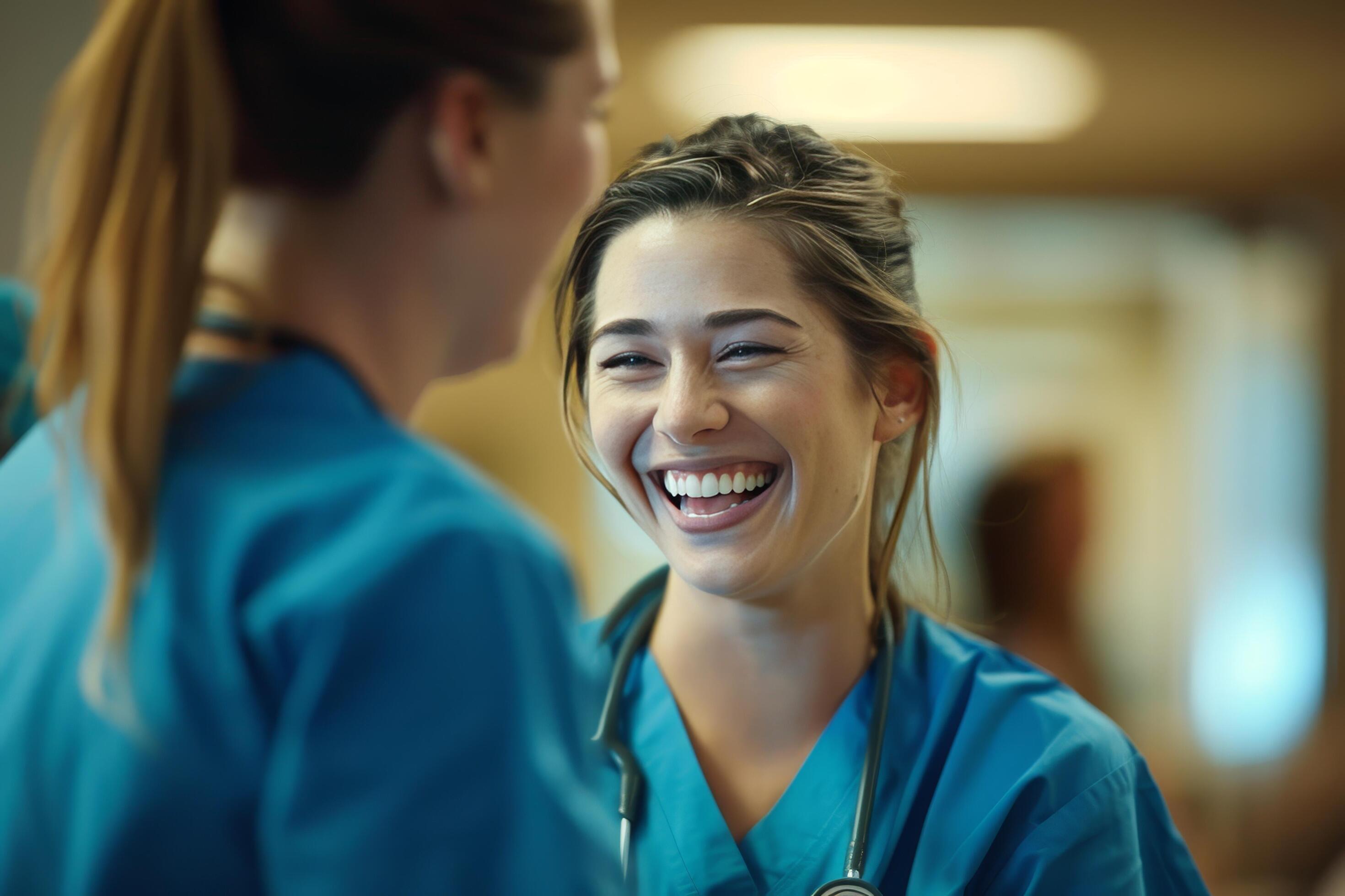 Two women in blue scrubs are smiling at each other Stock Free