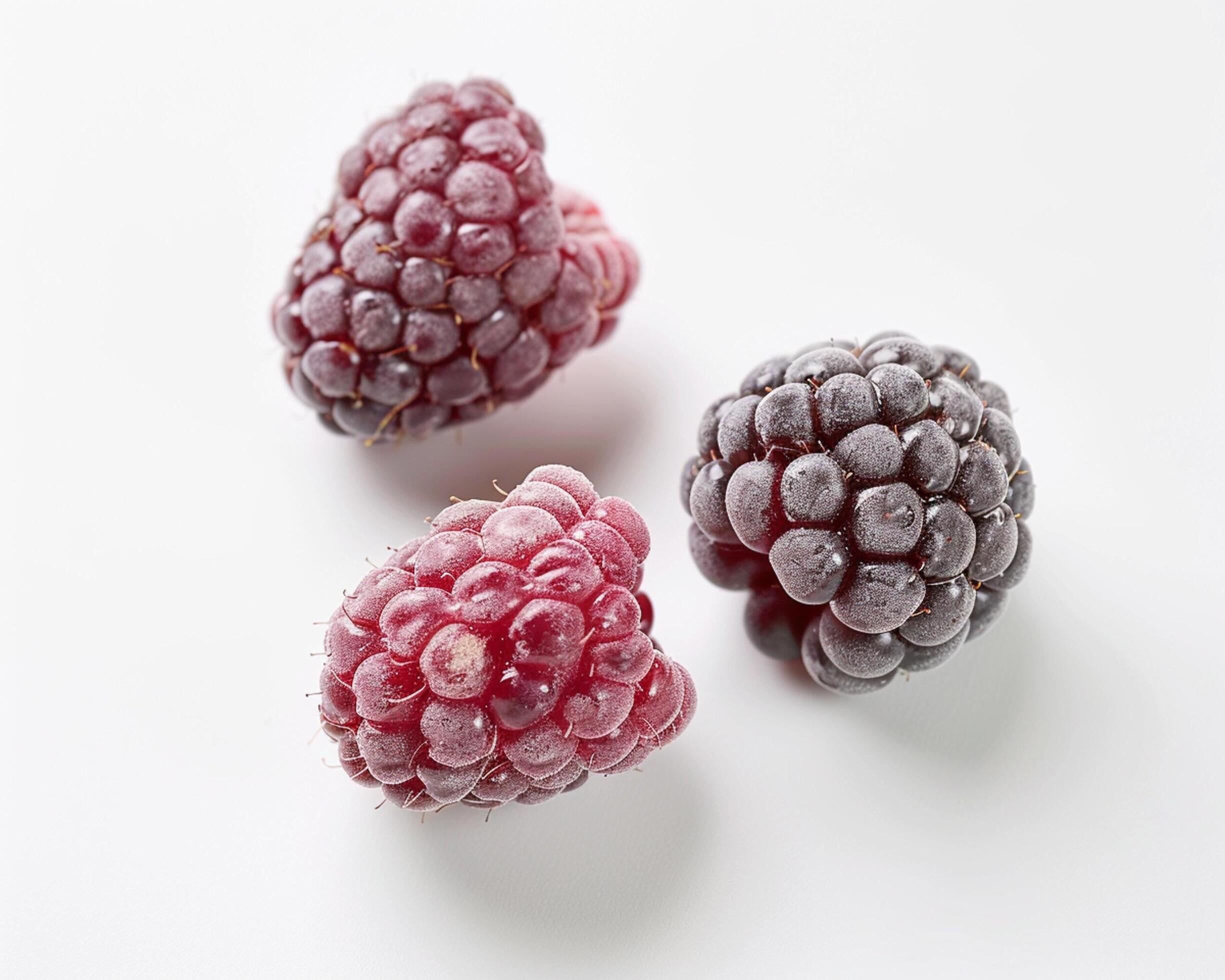 three raspberries are shown on a white surface Stock Free