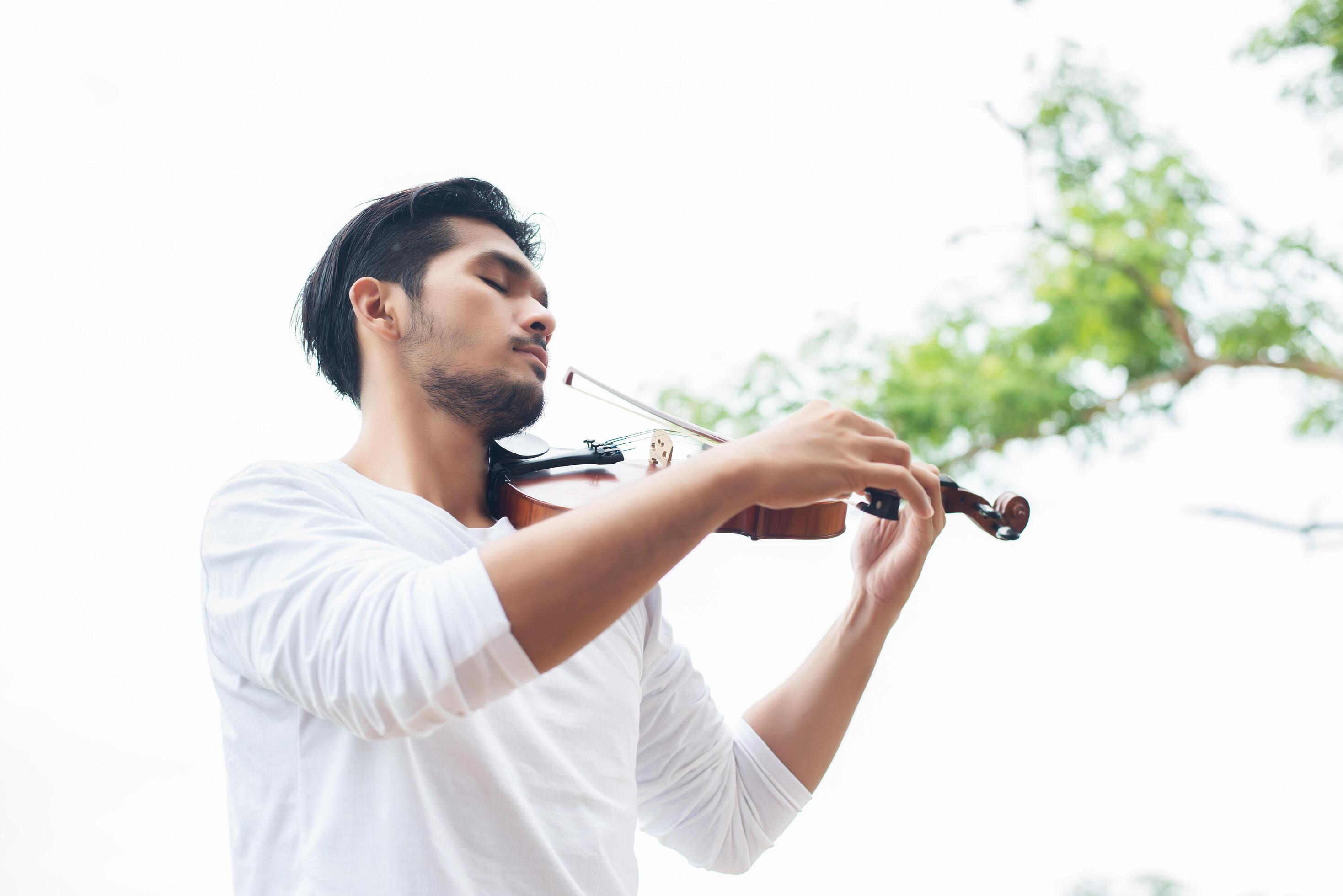 Young hipster musician man play violin in the nature outdoor lifestyle behind mountain. Stock Free