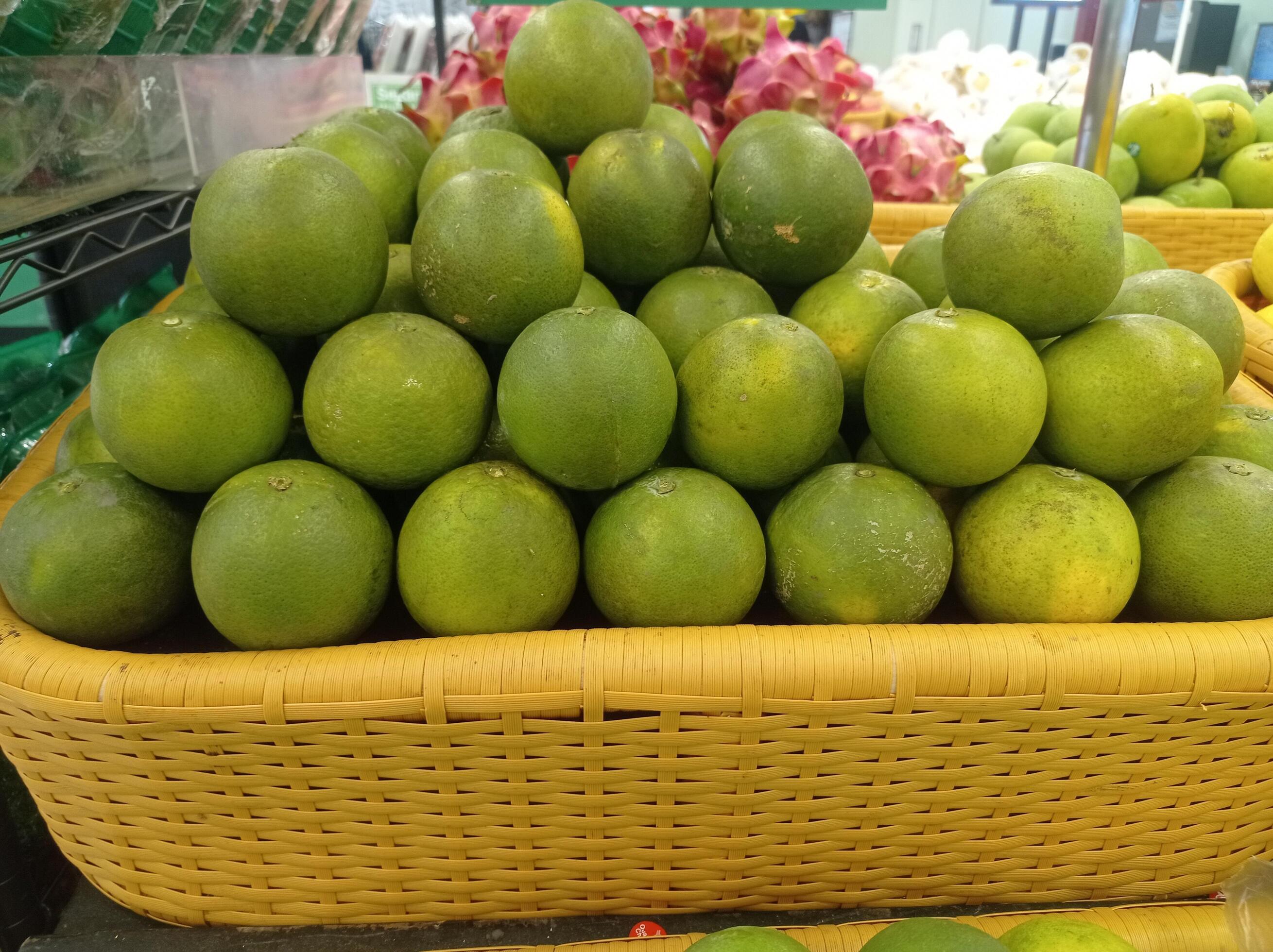 Fresh green oranges in mini market basket Stock Free