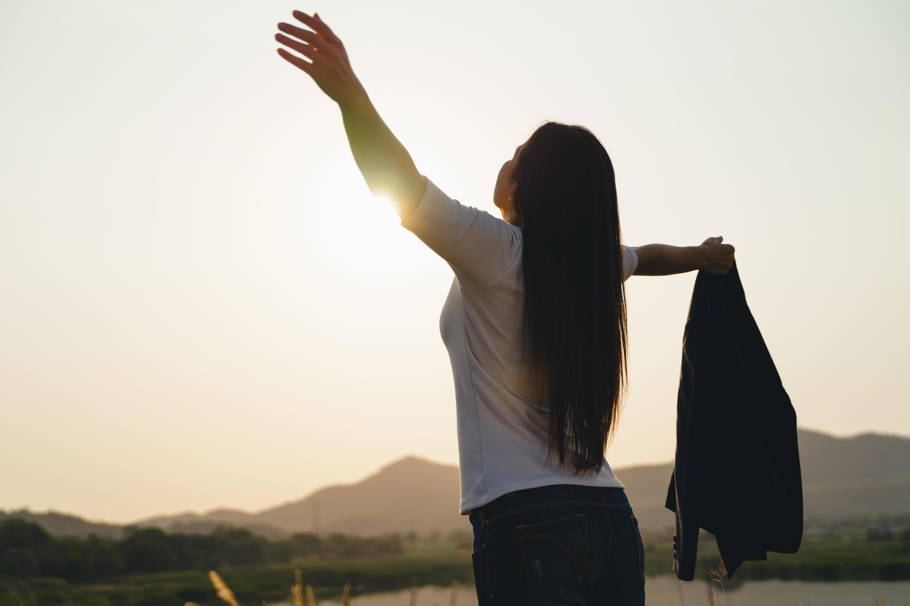 Happy business woman spreading arms and watching the mountain silhouette. Business success concept, freedom emotions Stock Free