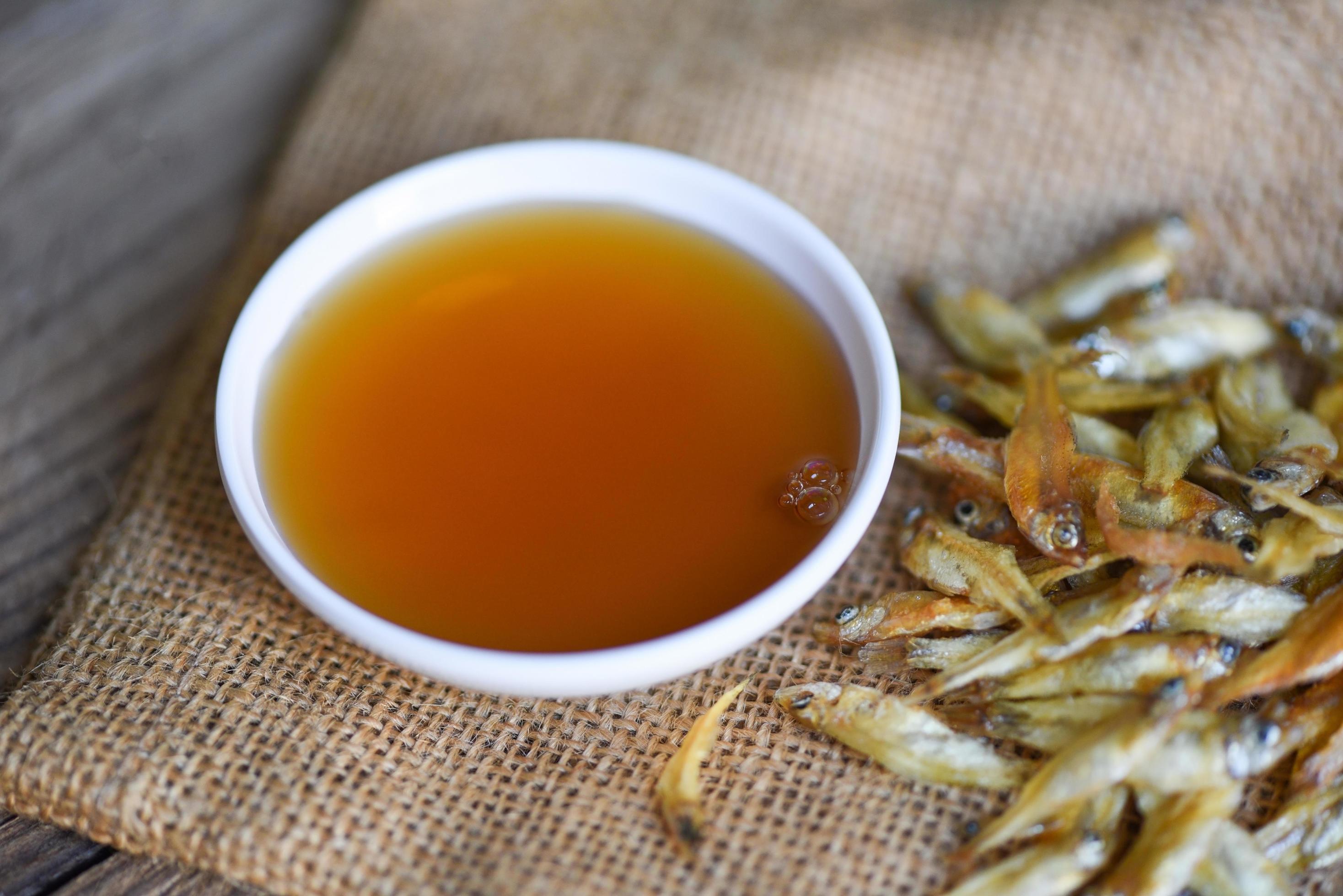 fish sauce on white bowl and small dried fish on sack, fish sauce obtained from fermentation fish or small aquatic animal, fermented foods Stock Free