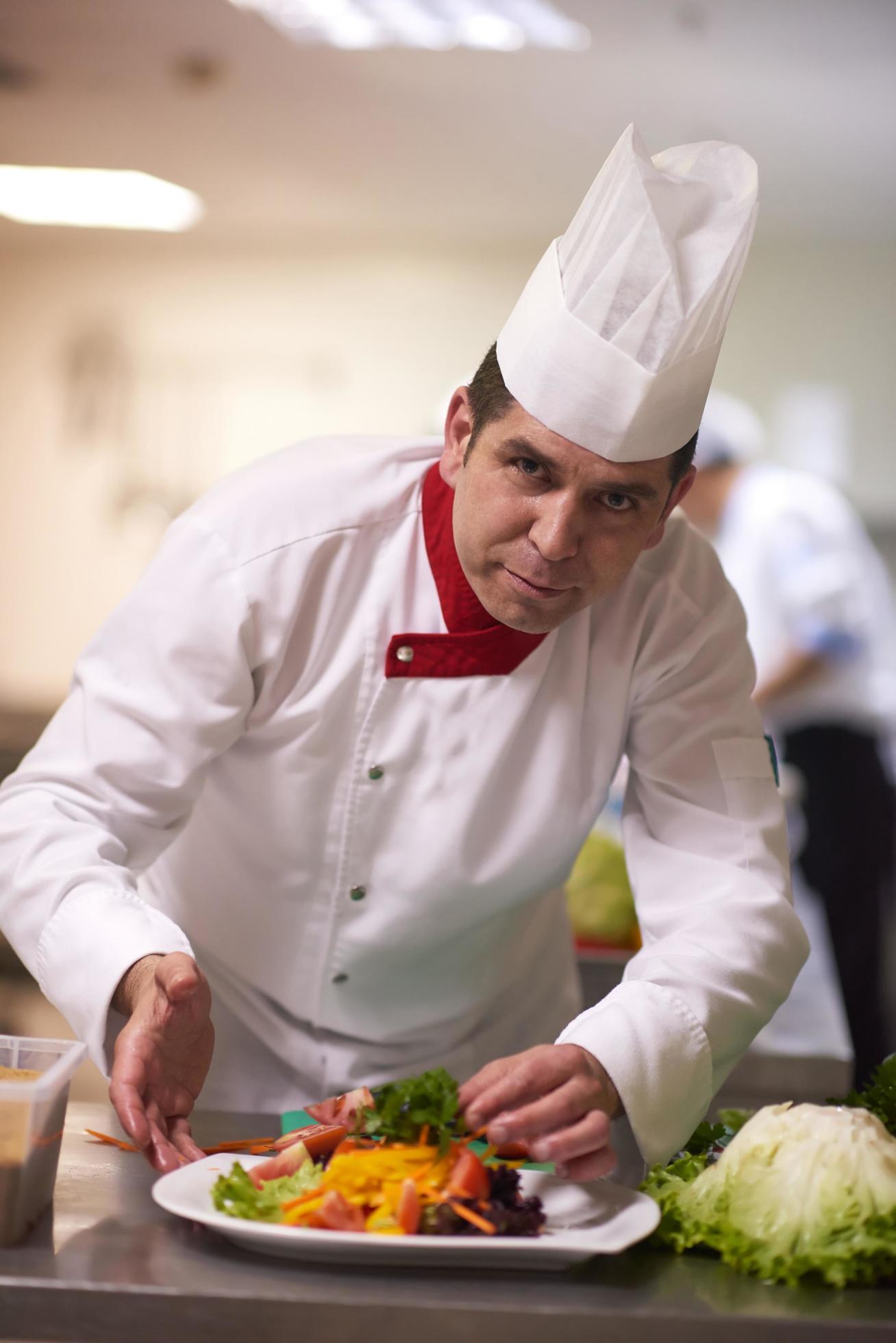 chef in hotel kitchen preparing and decorating food Stock Free