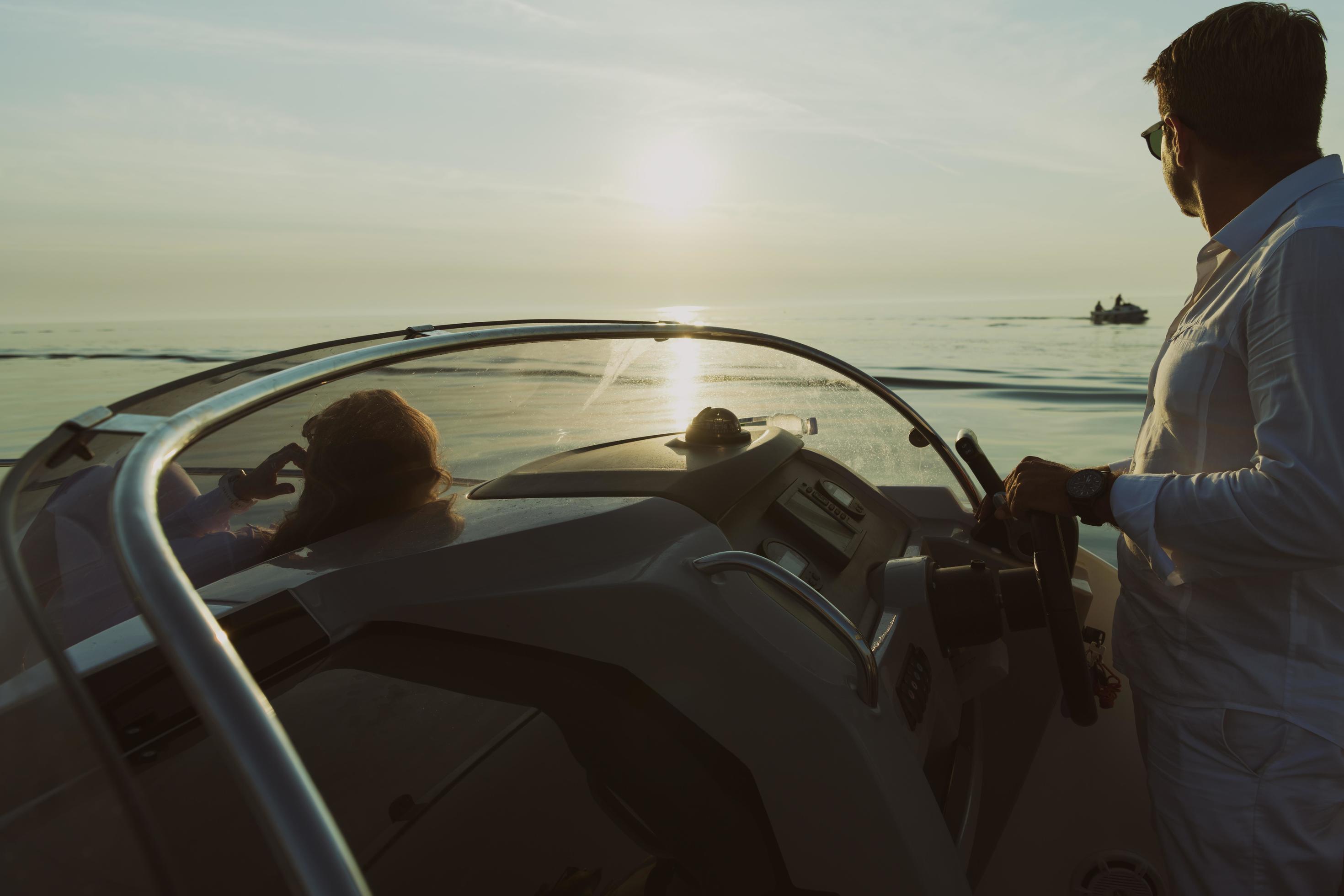 A senior couple in casual outfits with their son enjoy while riding a boat at sea at sunset. The concept of a happy family. Selective focus Stock Free