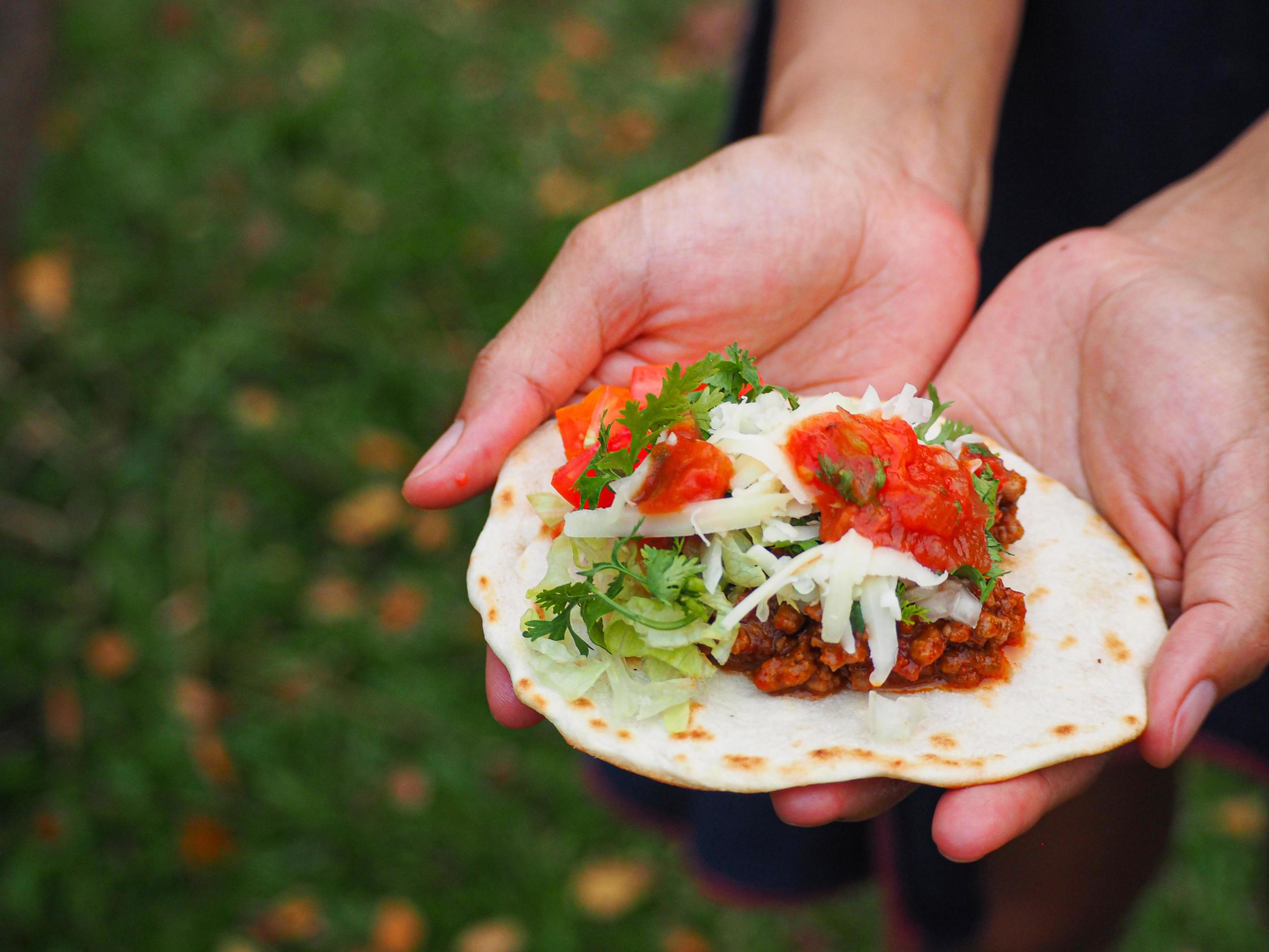 Taco Mexican food on hands young woman while standing in a garden Stock Free