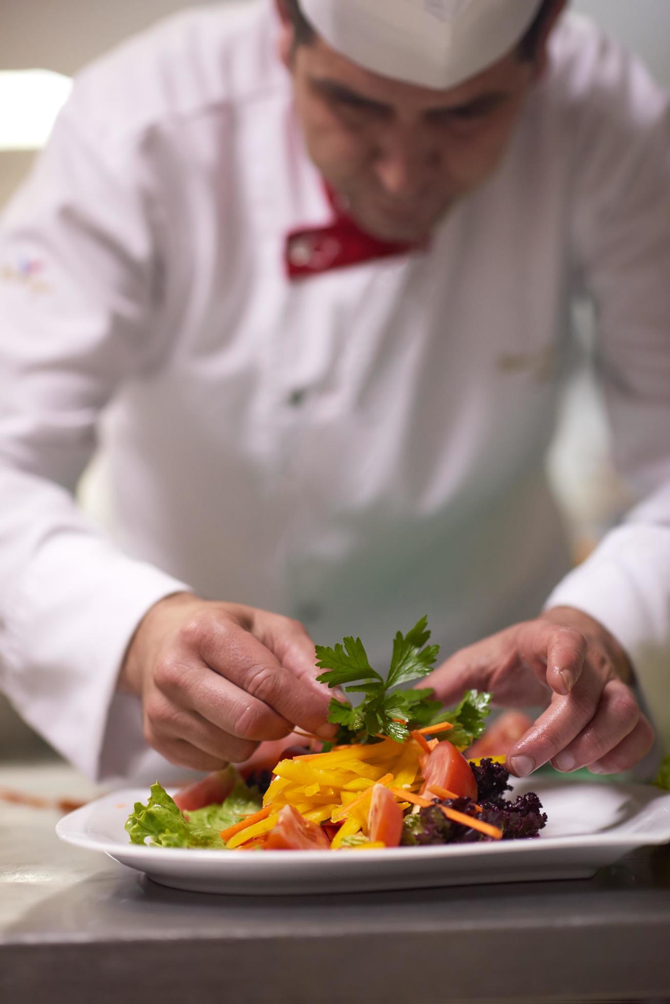 chef in hotel kitchen preparing and decorating food Stock Free