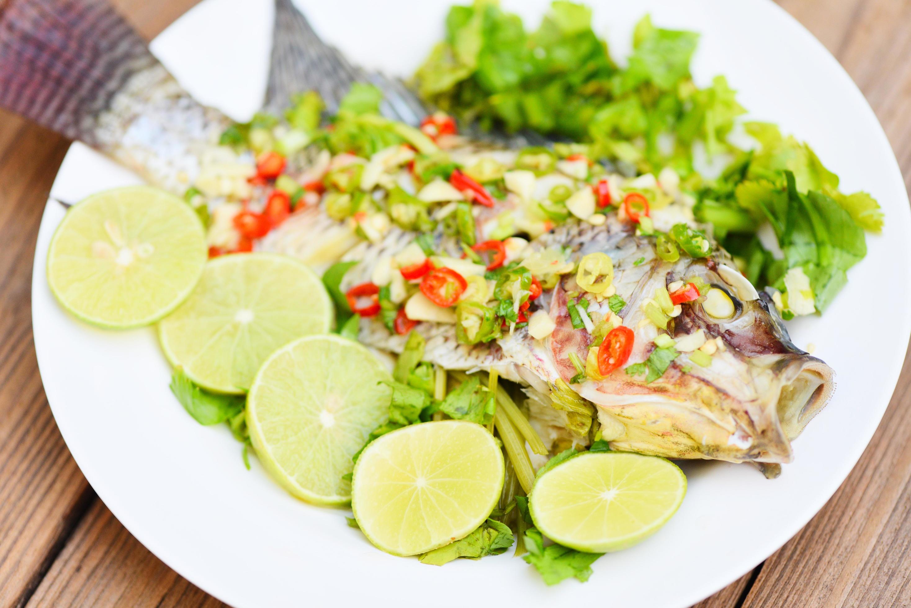 Steamed tilapia fish with chili and lime lemon sauce with herb and Vegetable on plate, Food cooked tilapia fish steam lime – Thai food Stock Free