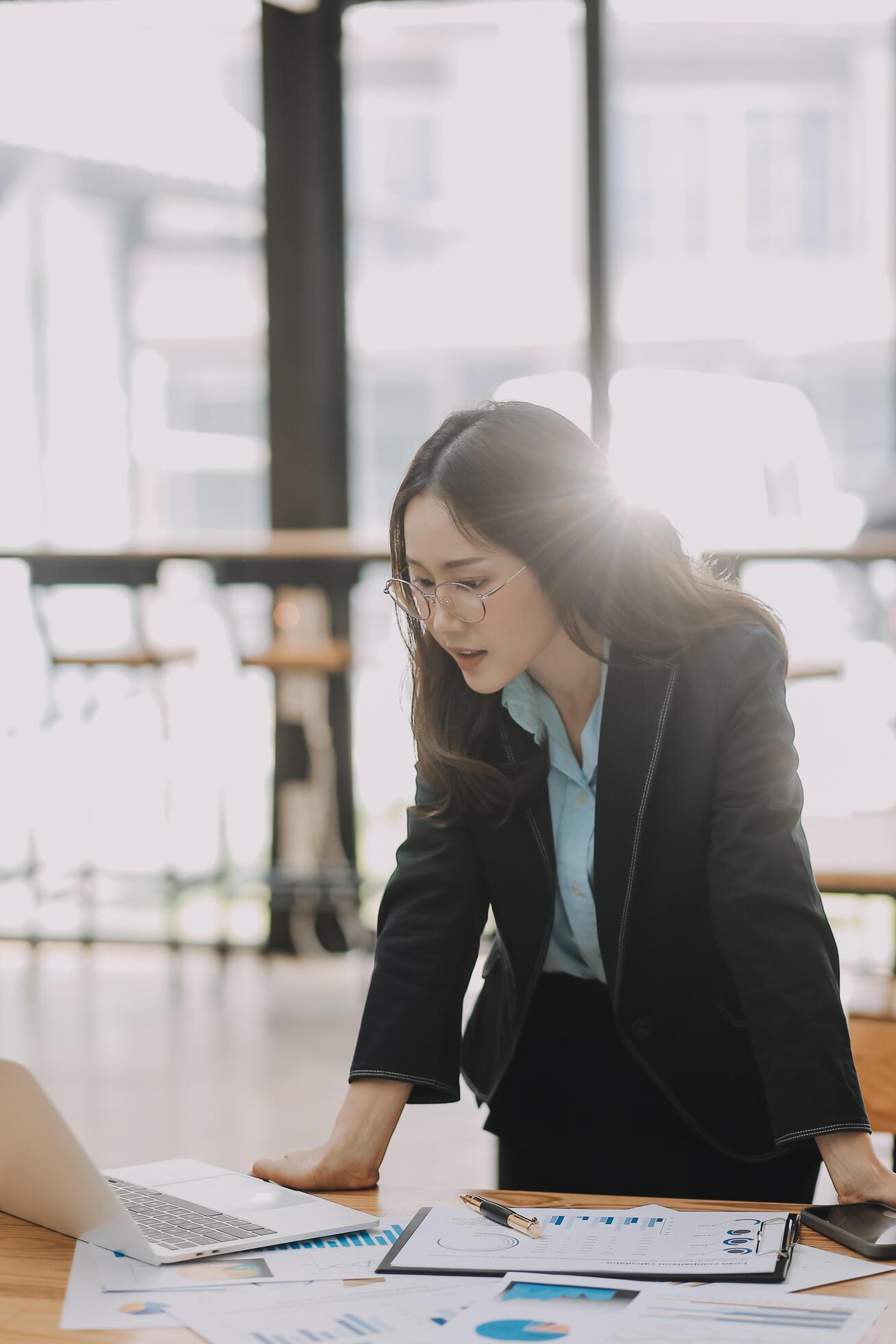 Young beautiful woman typing on tablet and laptop while sitting at the working wooden table modern office Stock Free