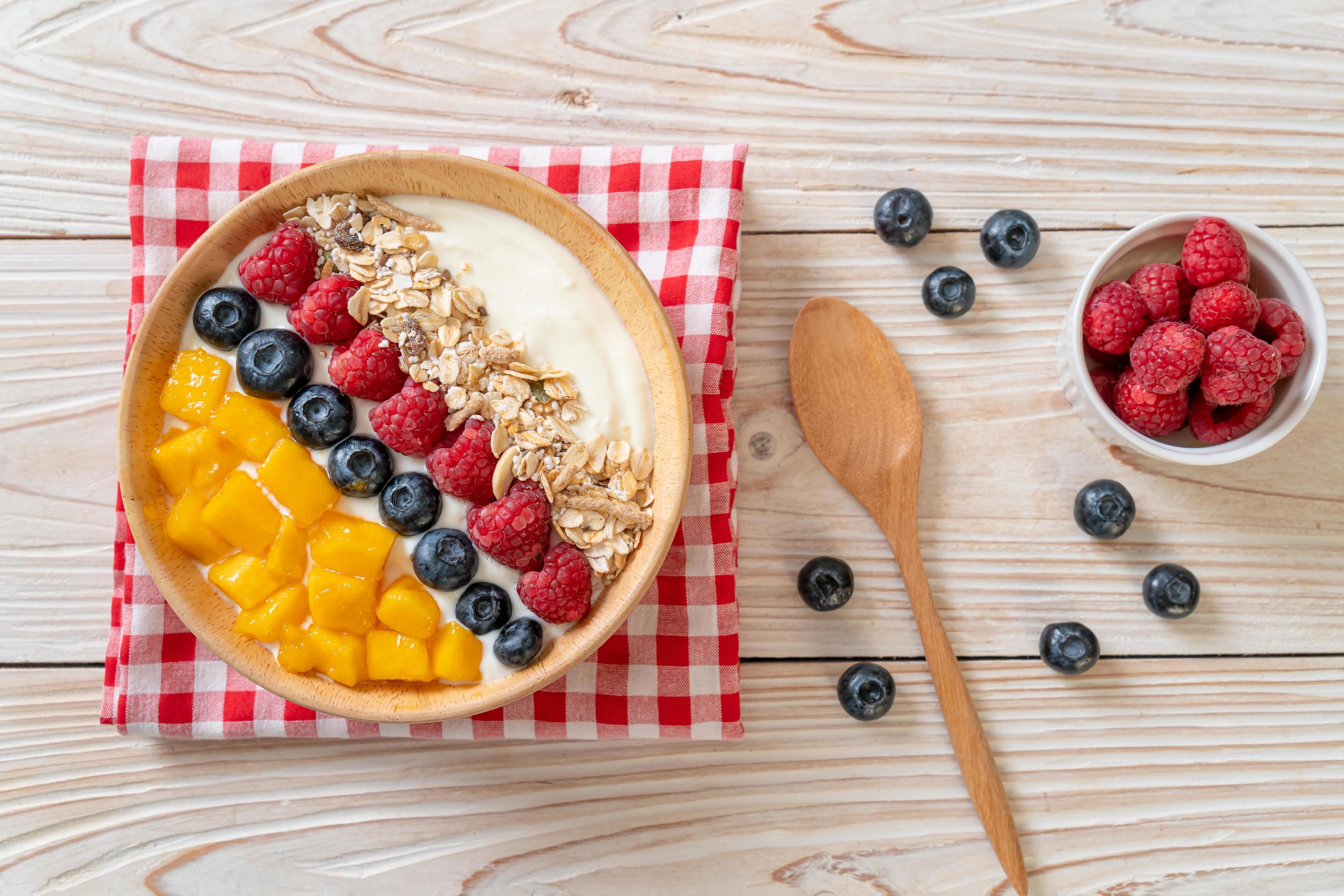 Homemade yogurt bowl with raspberry, blueberry, mango, and granola – healthy food style Stock Free