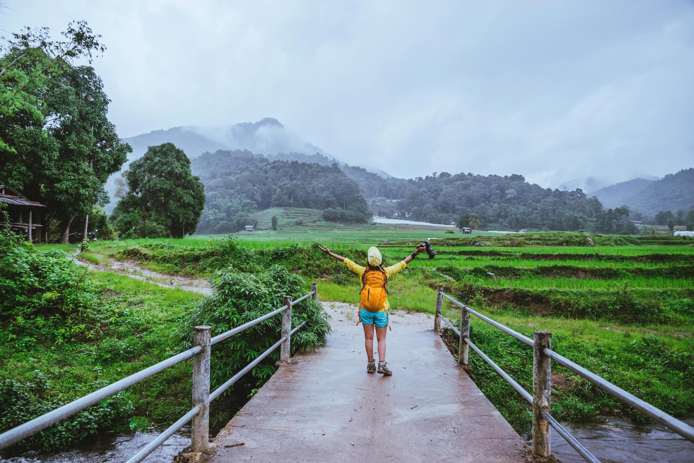 Asian women travel nature. Walking a photo the rice field and stop take a break relax on the bridge at ban Mae klang luang in rainy season. Stock Free