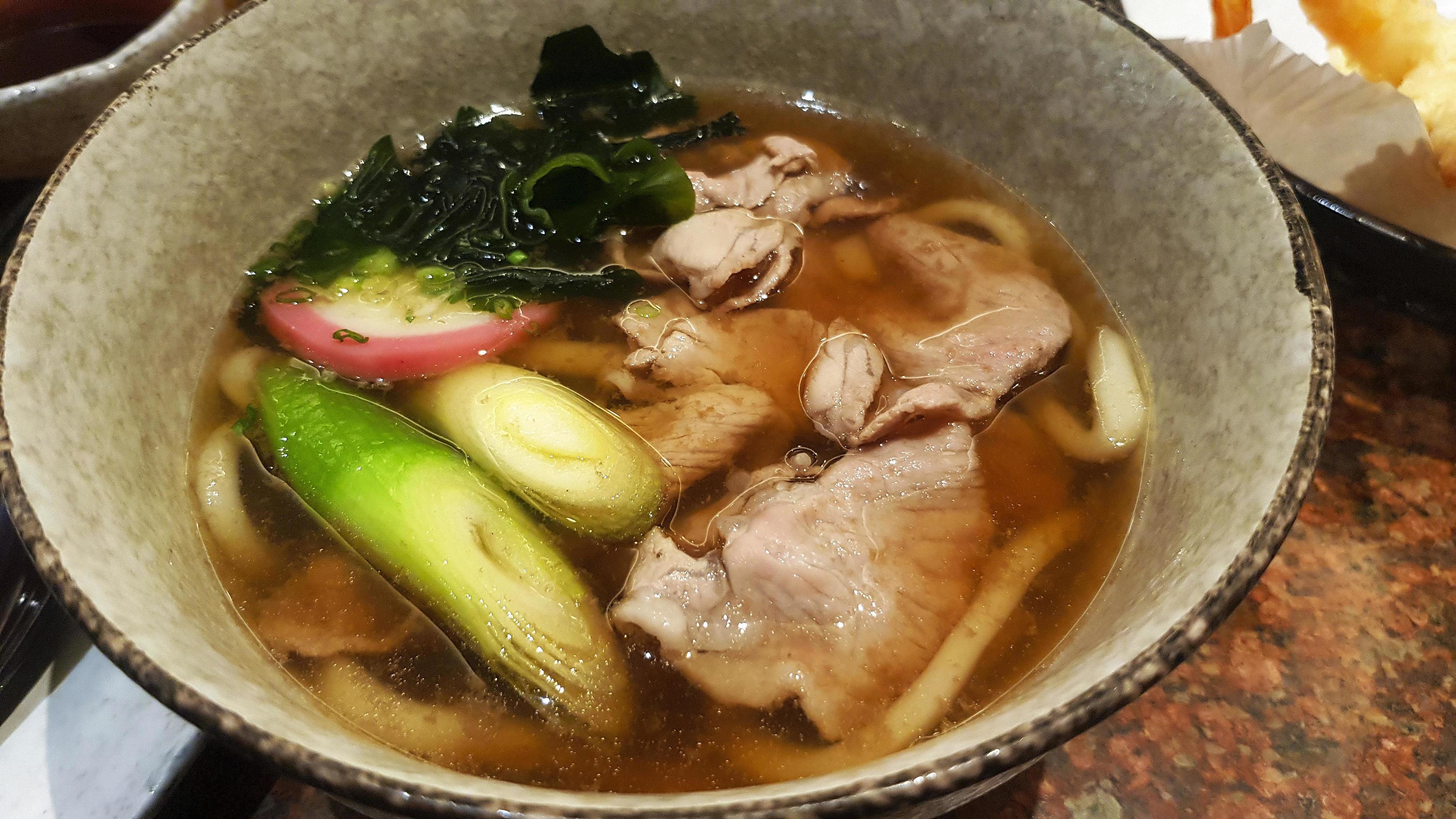 Close up Udon noodle with soup, sliced pork, seaweed or alga, Japanese spring onion on bowl at Japanese restaurant. Hot or Asian food. Stock Free