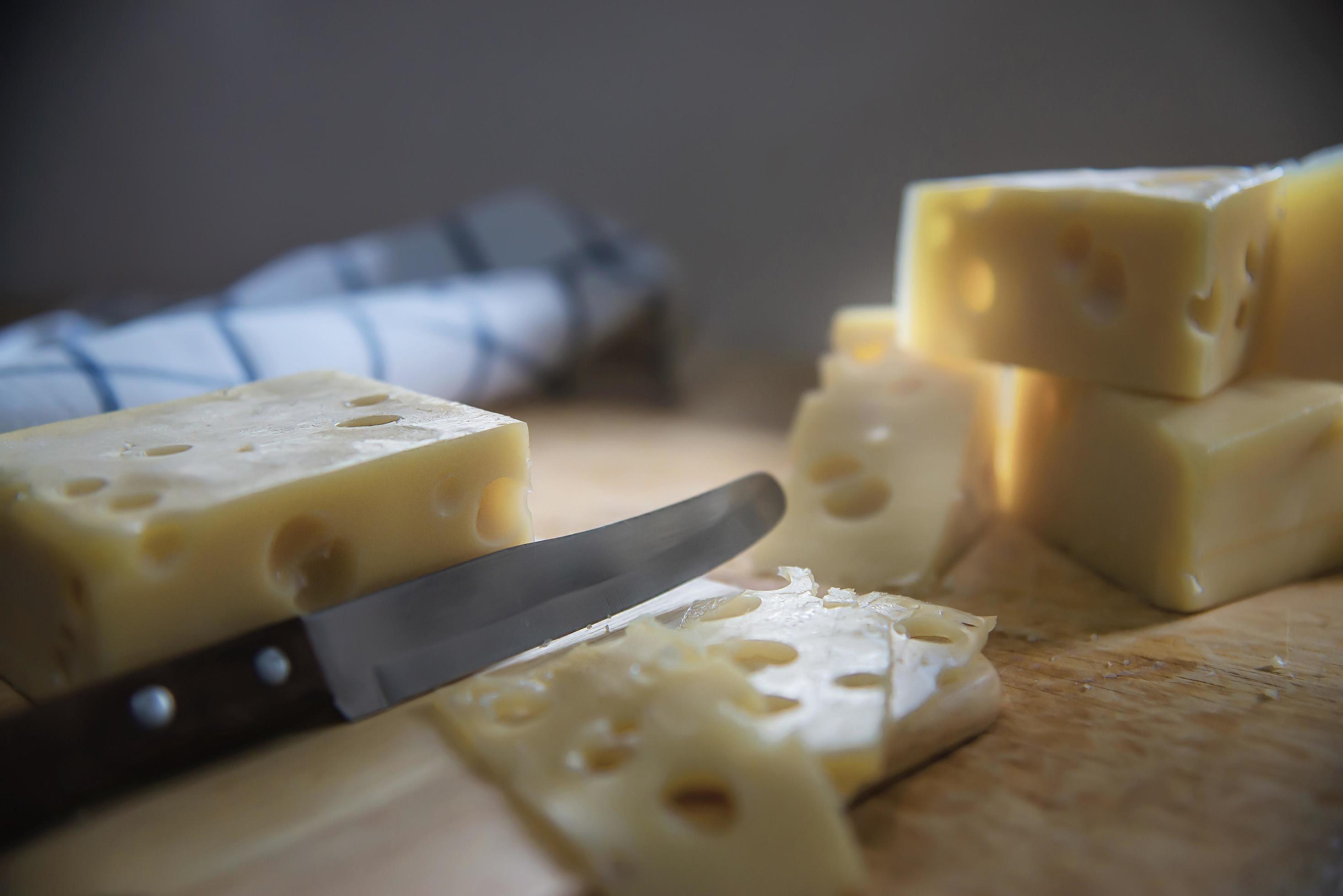 Woman preparing cheese for cook using cheese grater in the kitchen – people making food with cheese concept Stock Free