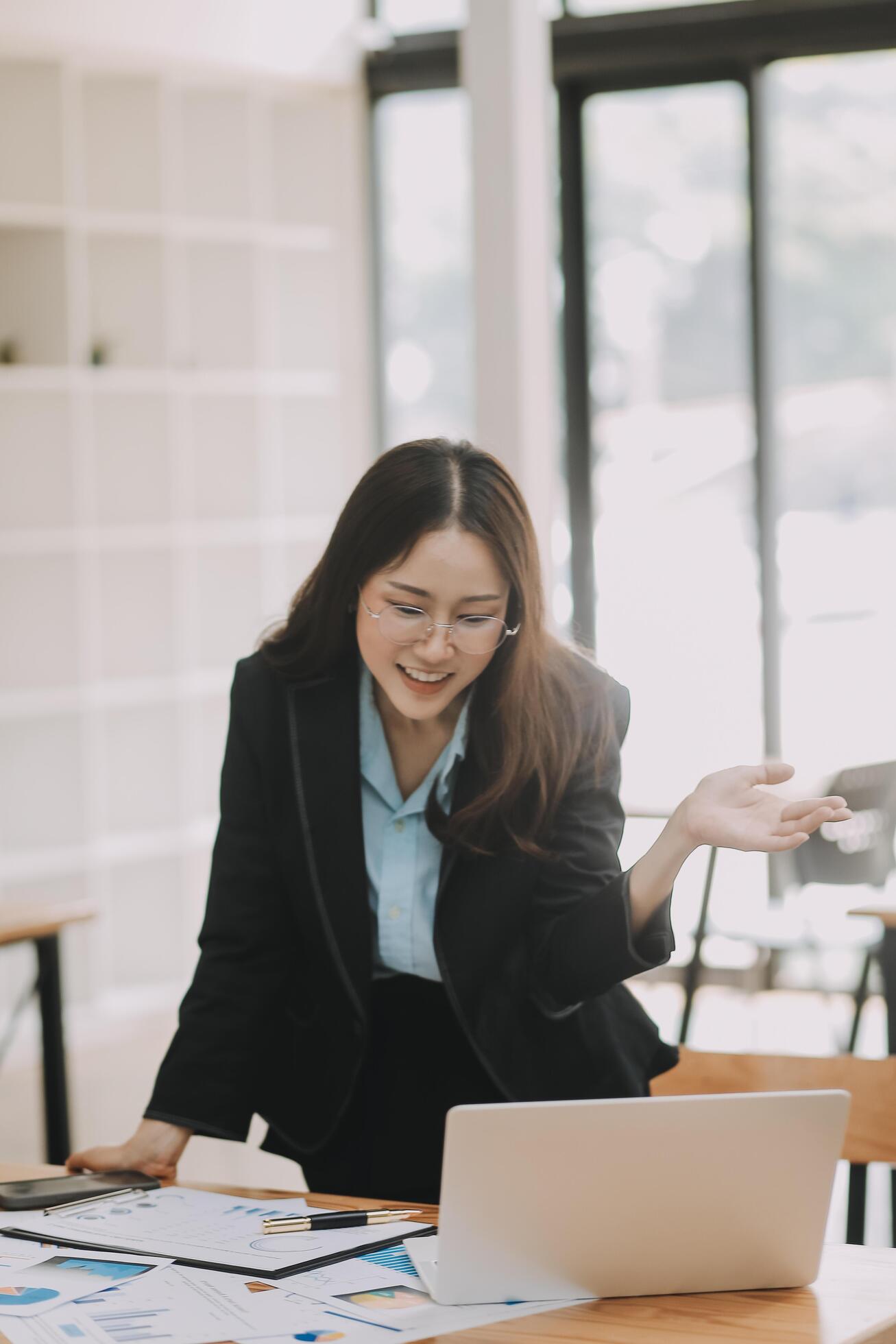 Happy young asian businesswoman sitting on her workplace in the office. Young woman working at laptop in the office. Stock Free