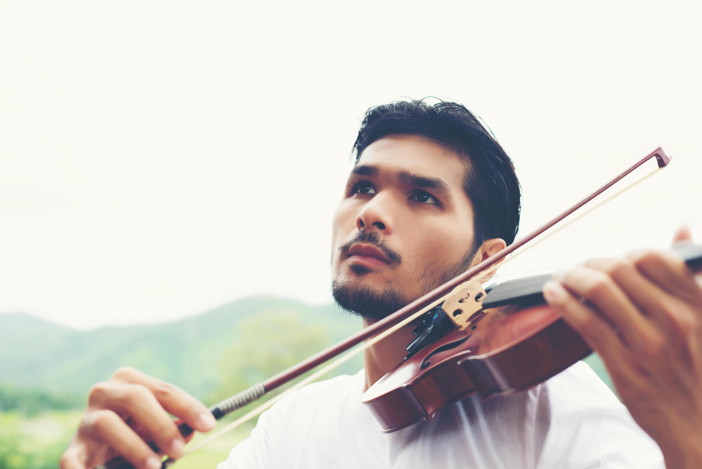 Young hipster musician man play violin in the nature outdoor lifestyle behind mountain. Stock Free