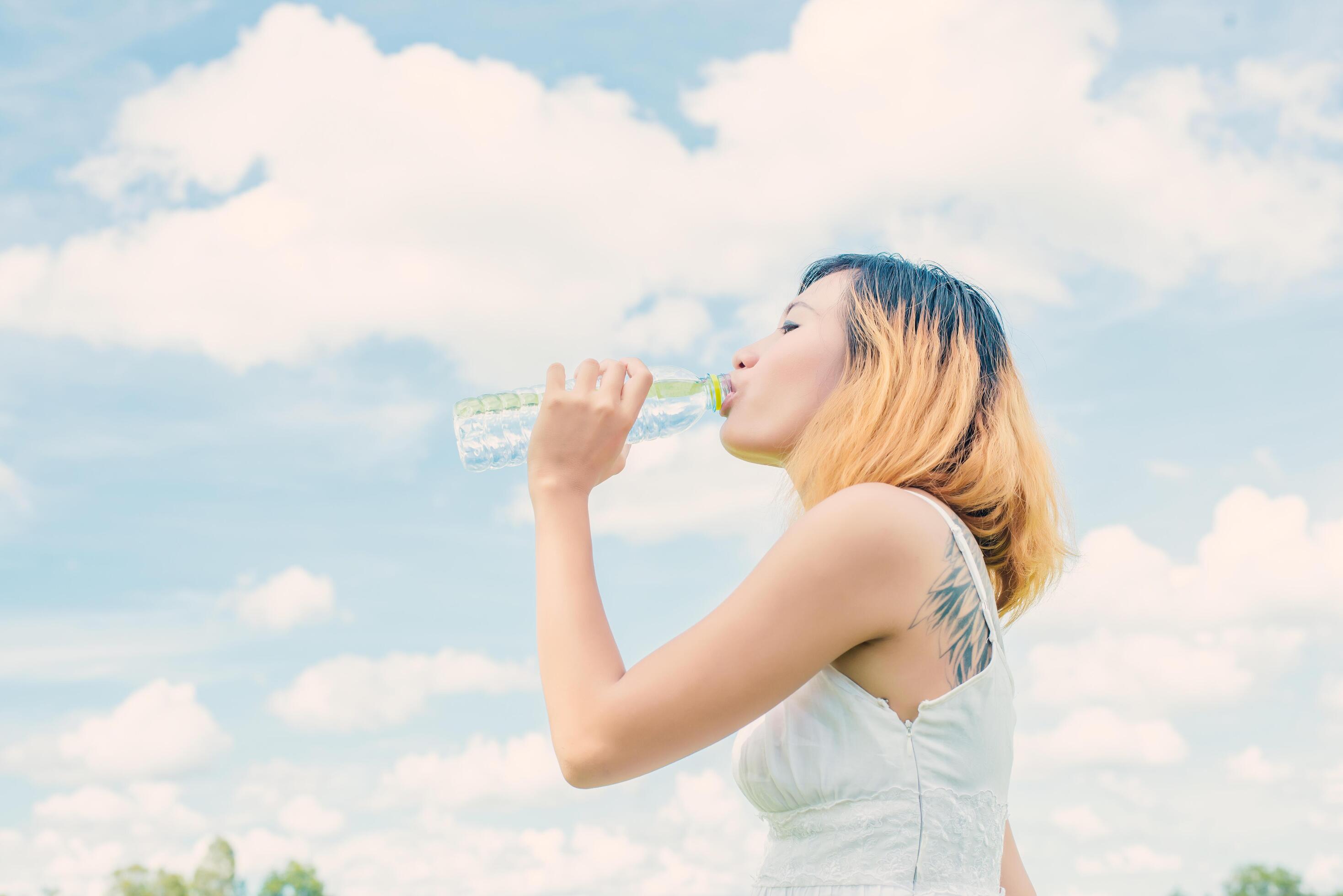 Women lifestyle concept young beautiful woman with white dress drinking water at summer green park. Stock Free