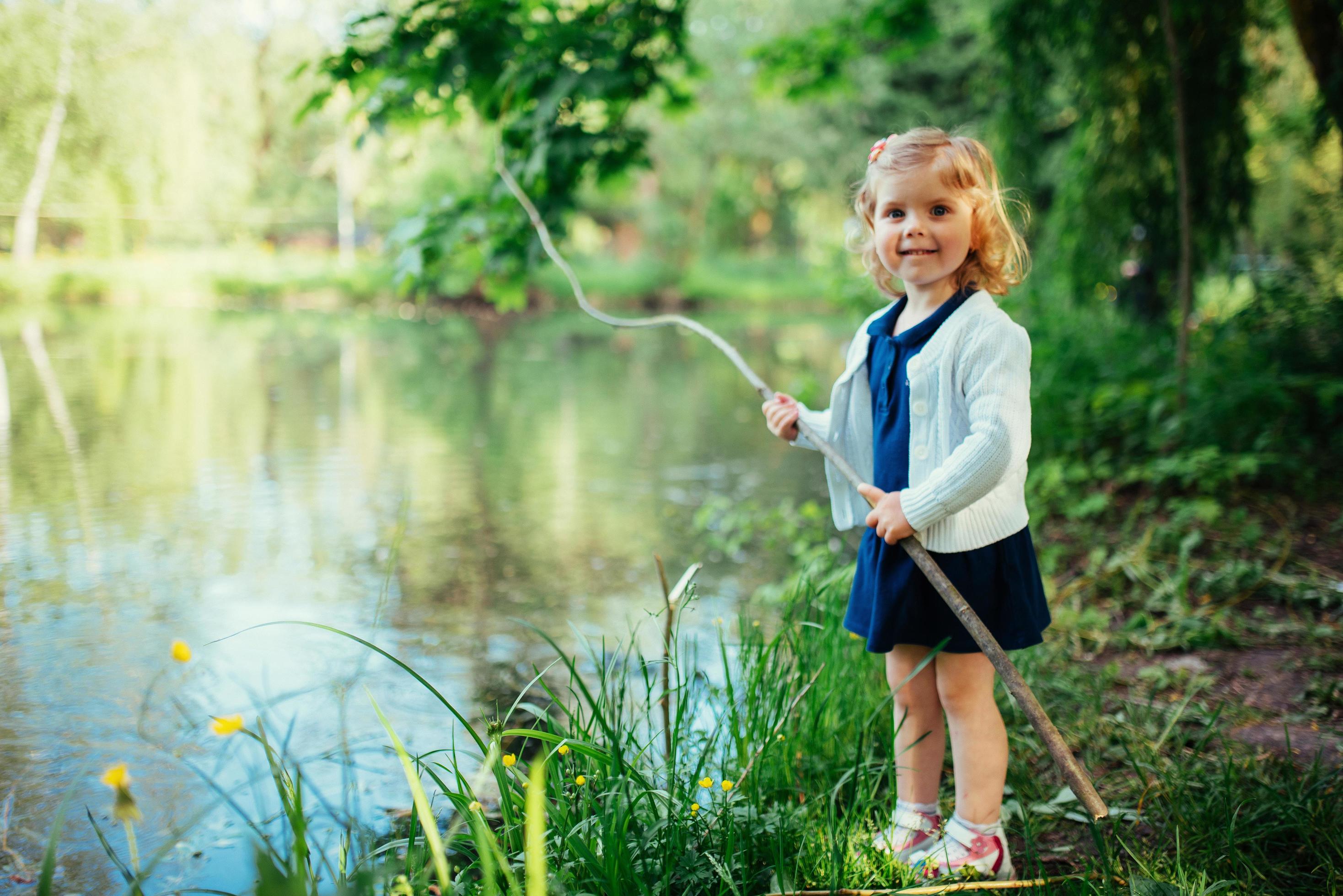 Cute little blonde girl is against the background of water and g Stock Free