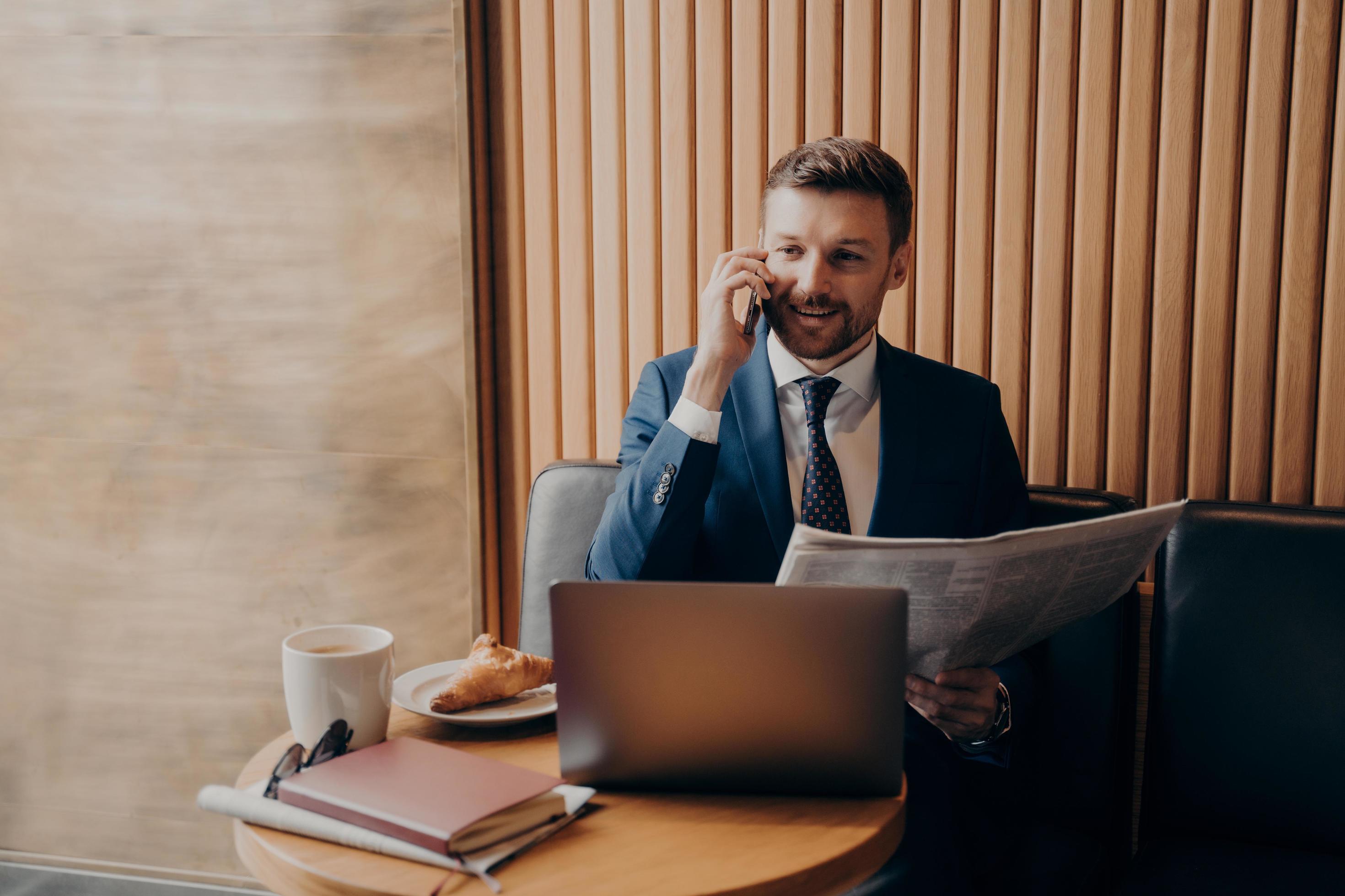 Business owner talking on phone after reading news, sitting in cafe Stock Free