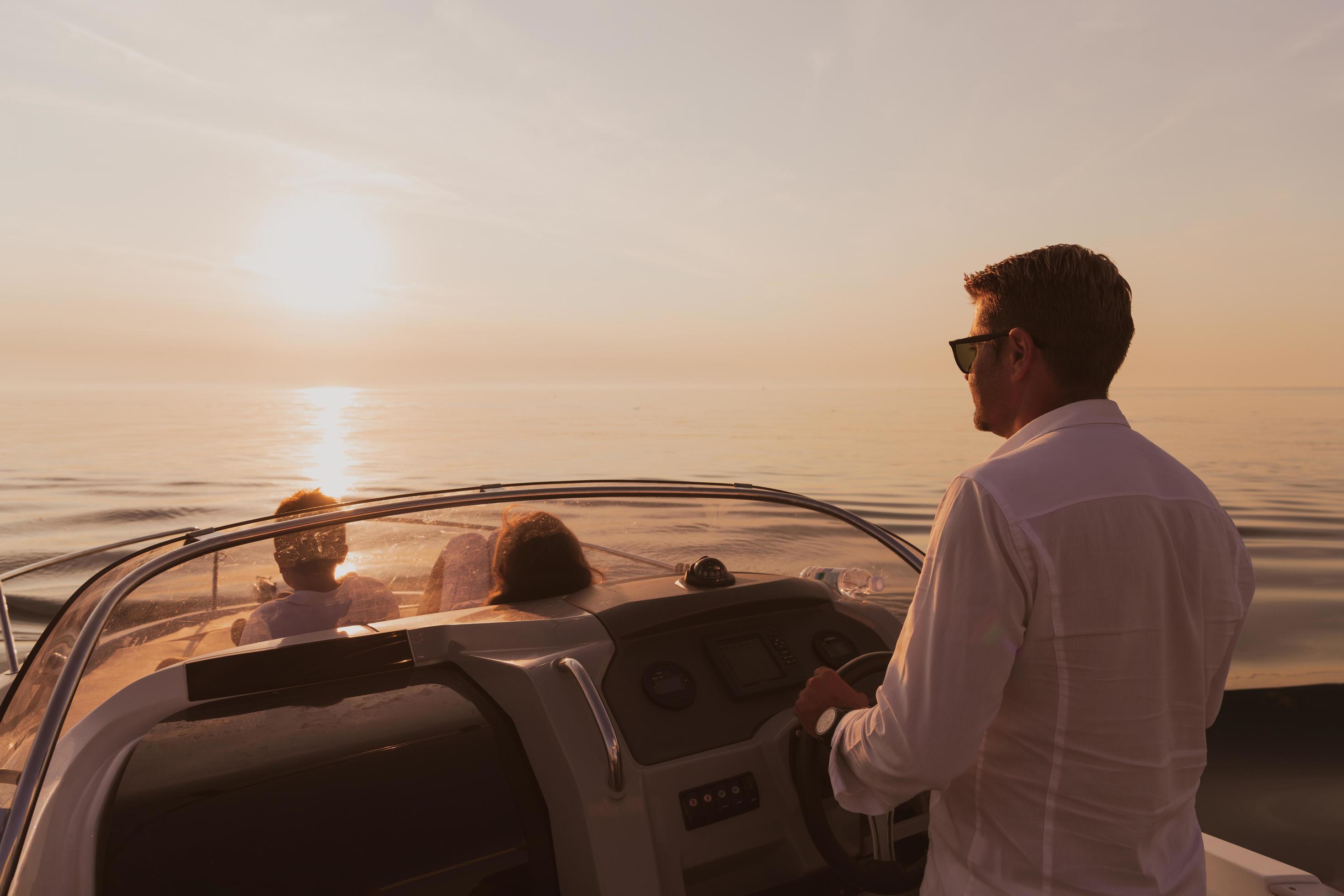 A senior couple in casual outfits with their son enjoy while riding a boat at sea at sunset. The concept of a happy family. Selective focus Stock Free