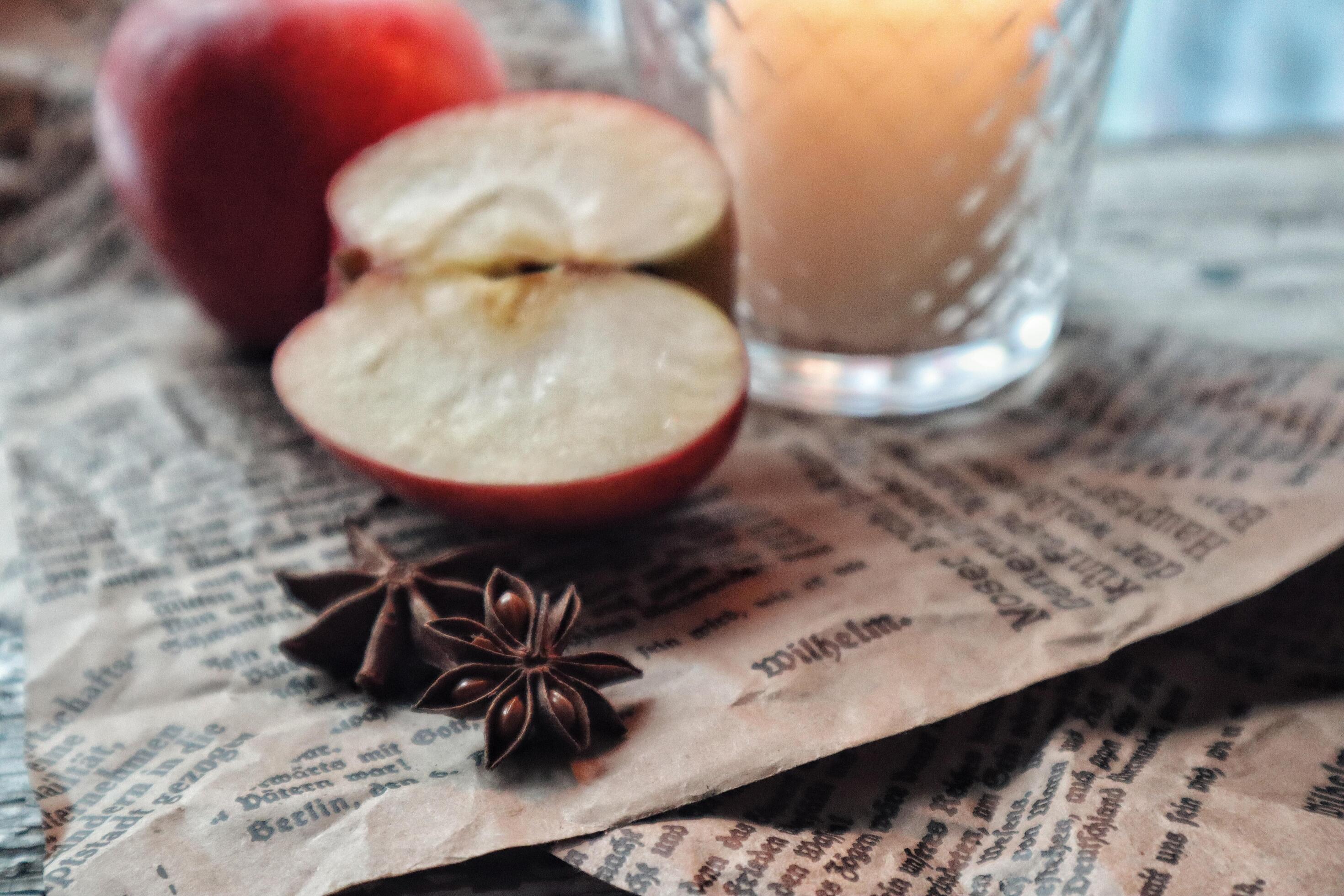 Cozy still life food photography Red apples cut half with anise spices on a craft paper next to a candle Stock Free