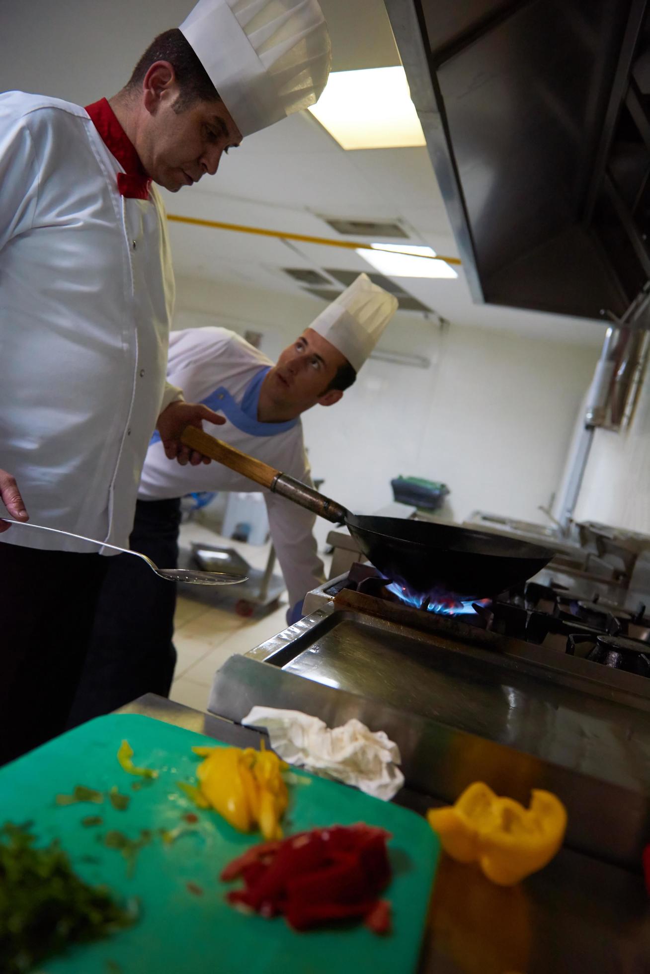 chef in hotel kitchen prepare food with fire Stock Free