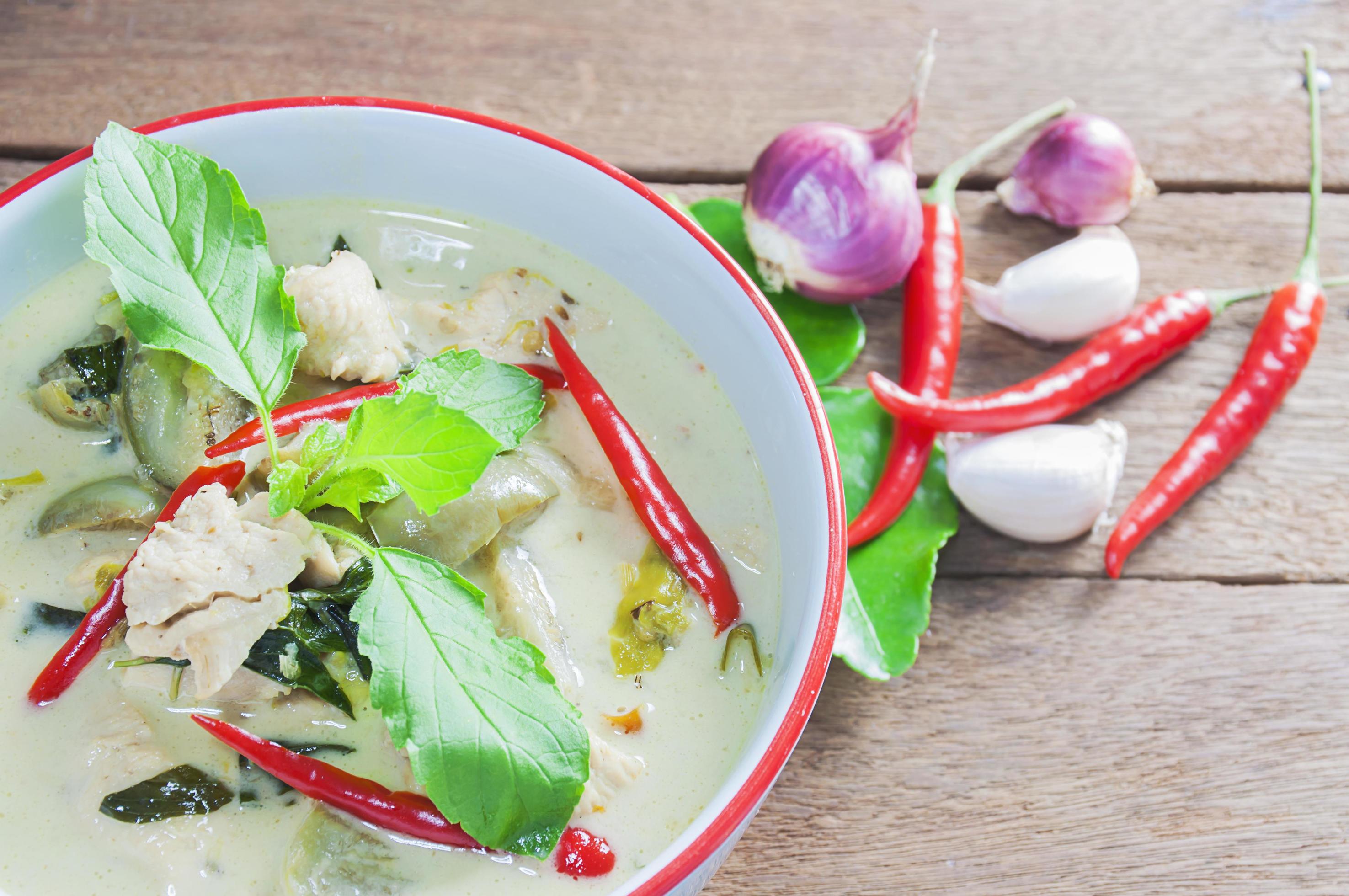 Green chicken curry with raw spicy ingredient Thai traditional food on brown wooden background Stock Free