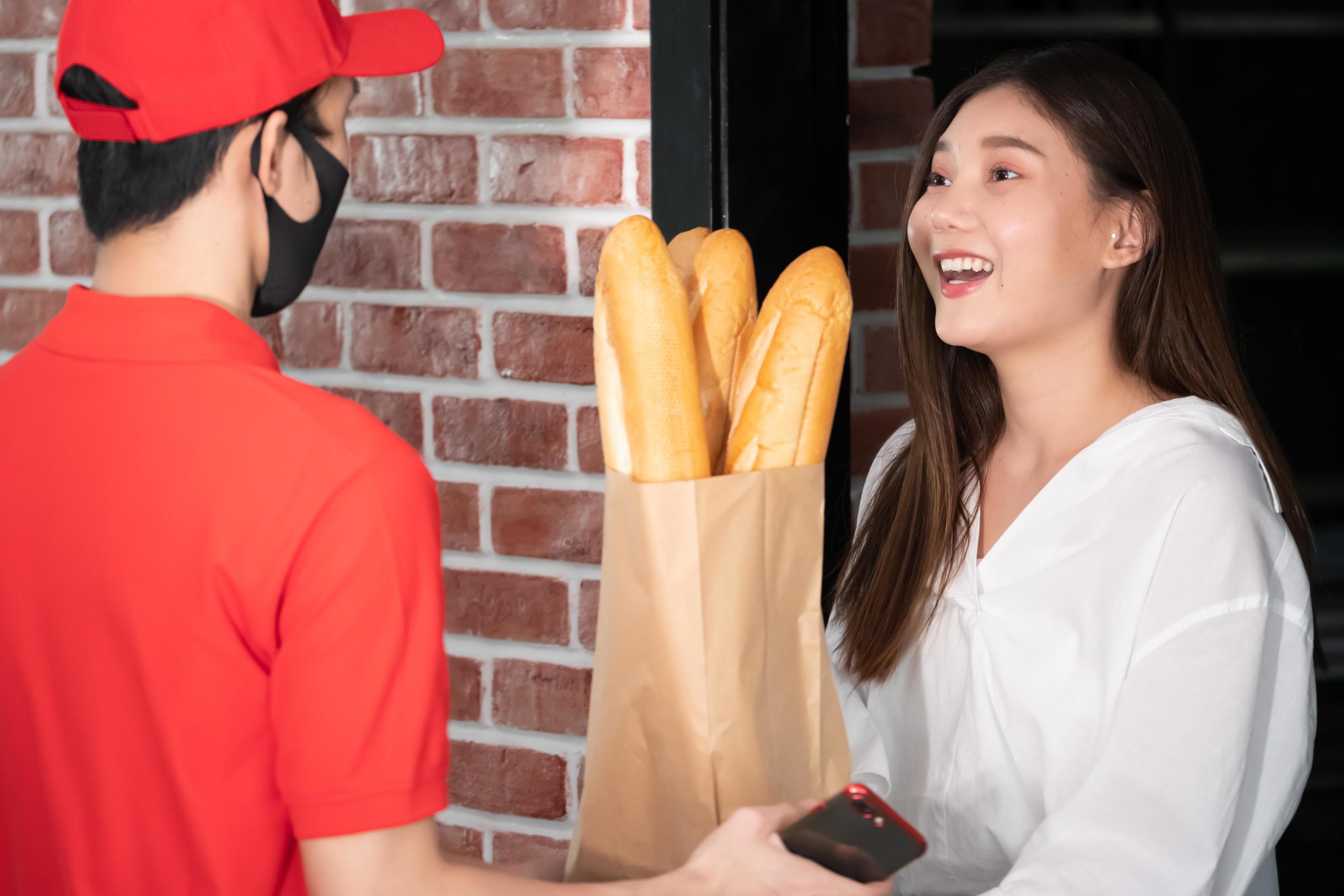 Happy woman recieving food from food deliveryman Stock Free