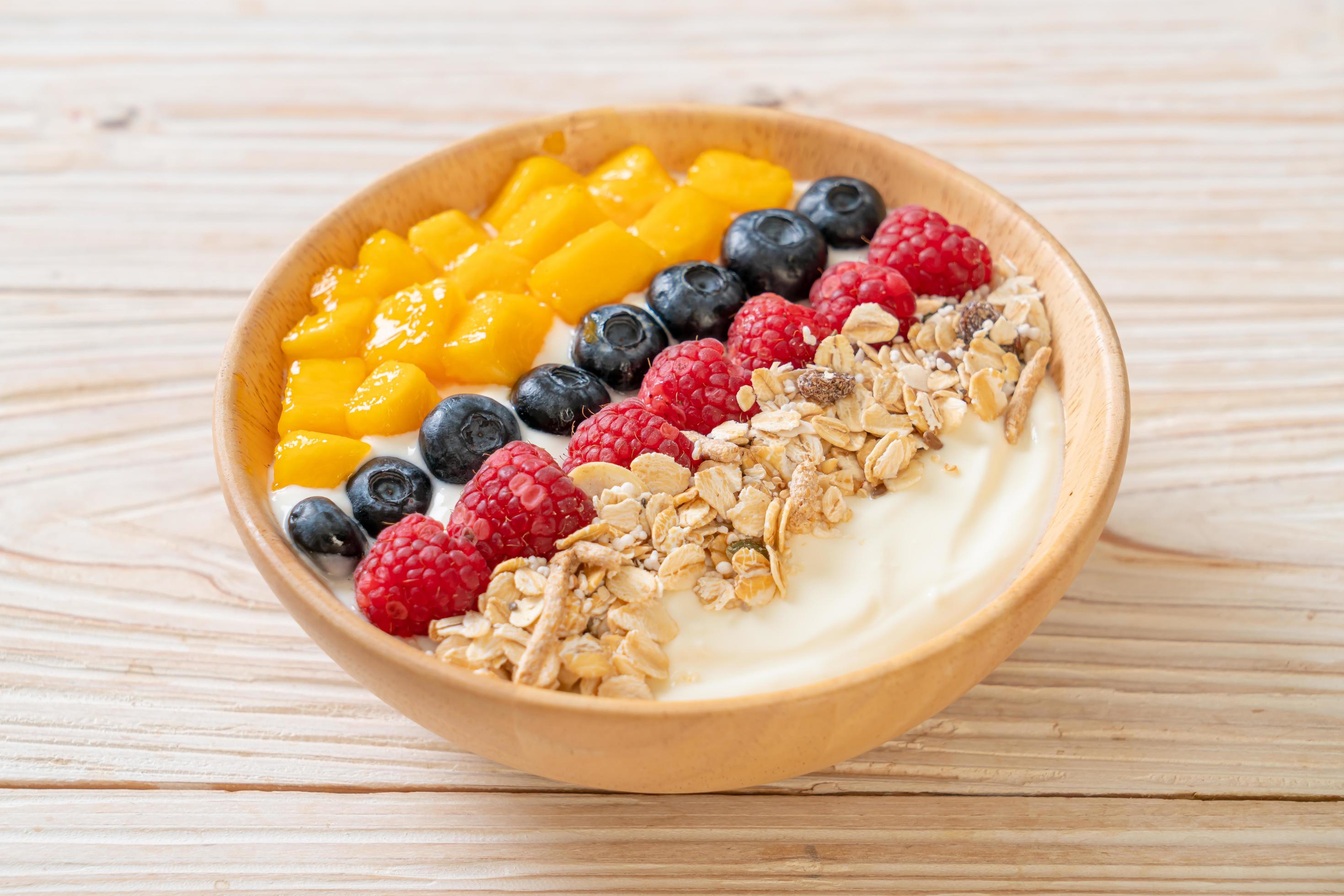 Homemade yogurt bowl with raspberry, blueberry, mango, and granola – healthy food style Stock Free