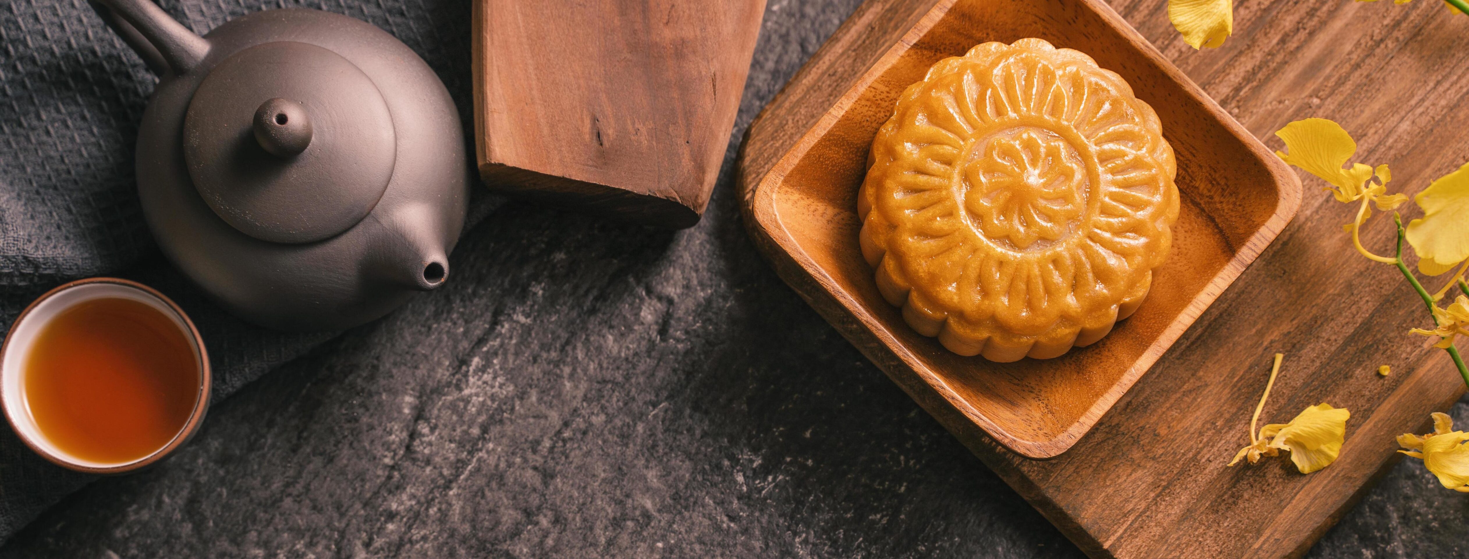 
									Mid-Autumn Festival traditional food concept – Beautiful Moon cake on black slate table with tea, pastry mold, flower, top view, flat lay, copy space Stock Free