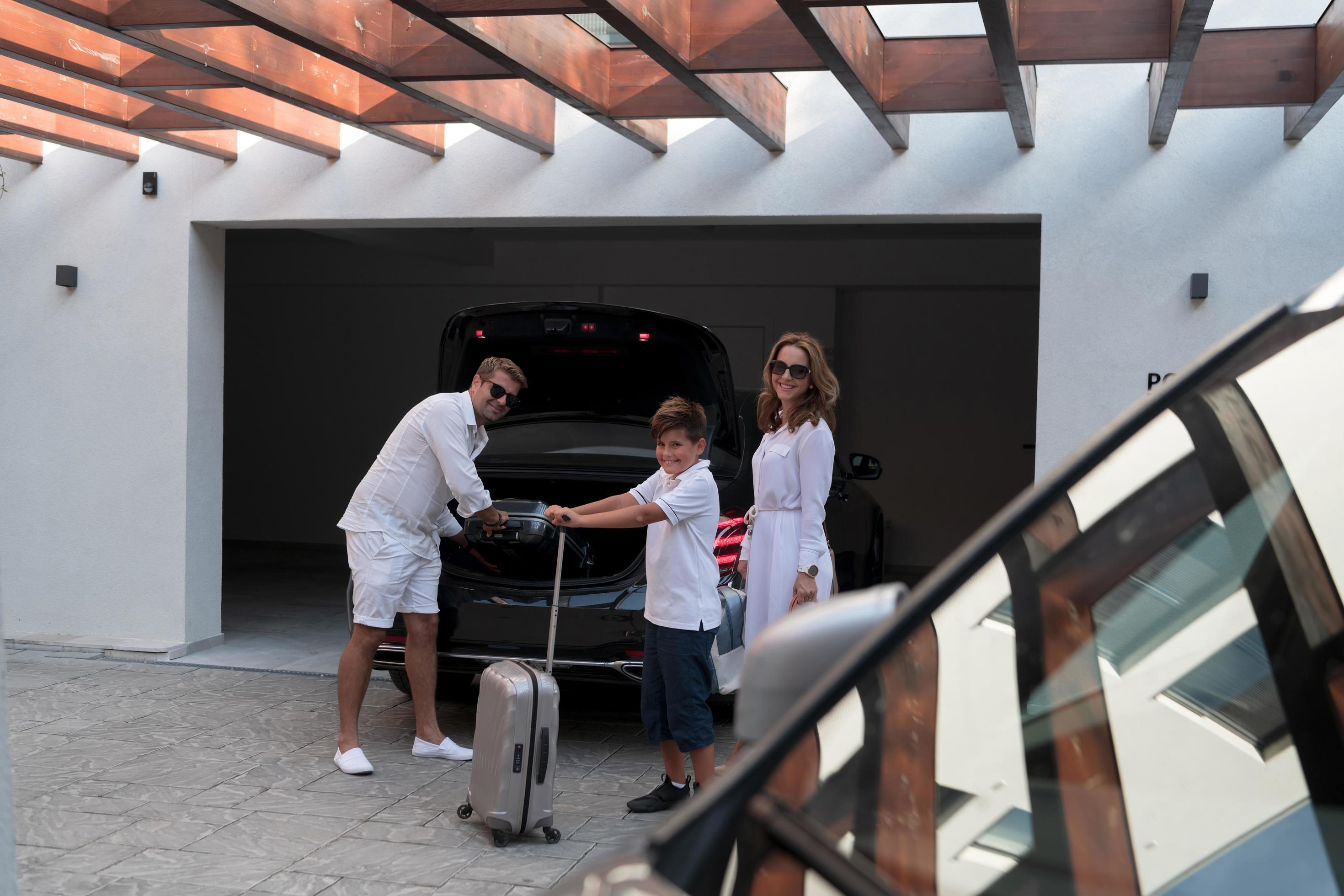 A photo of a modern family carrying suitcases from a garage to their luxury seaside home during a vacation. Vacation concept. Selective focus Stock Free