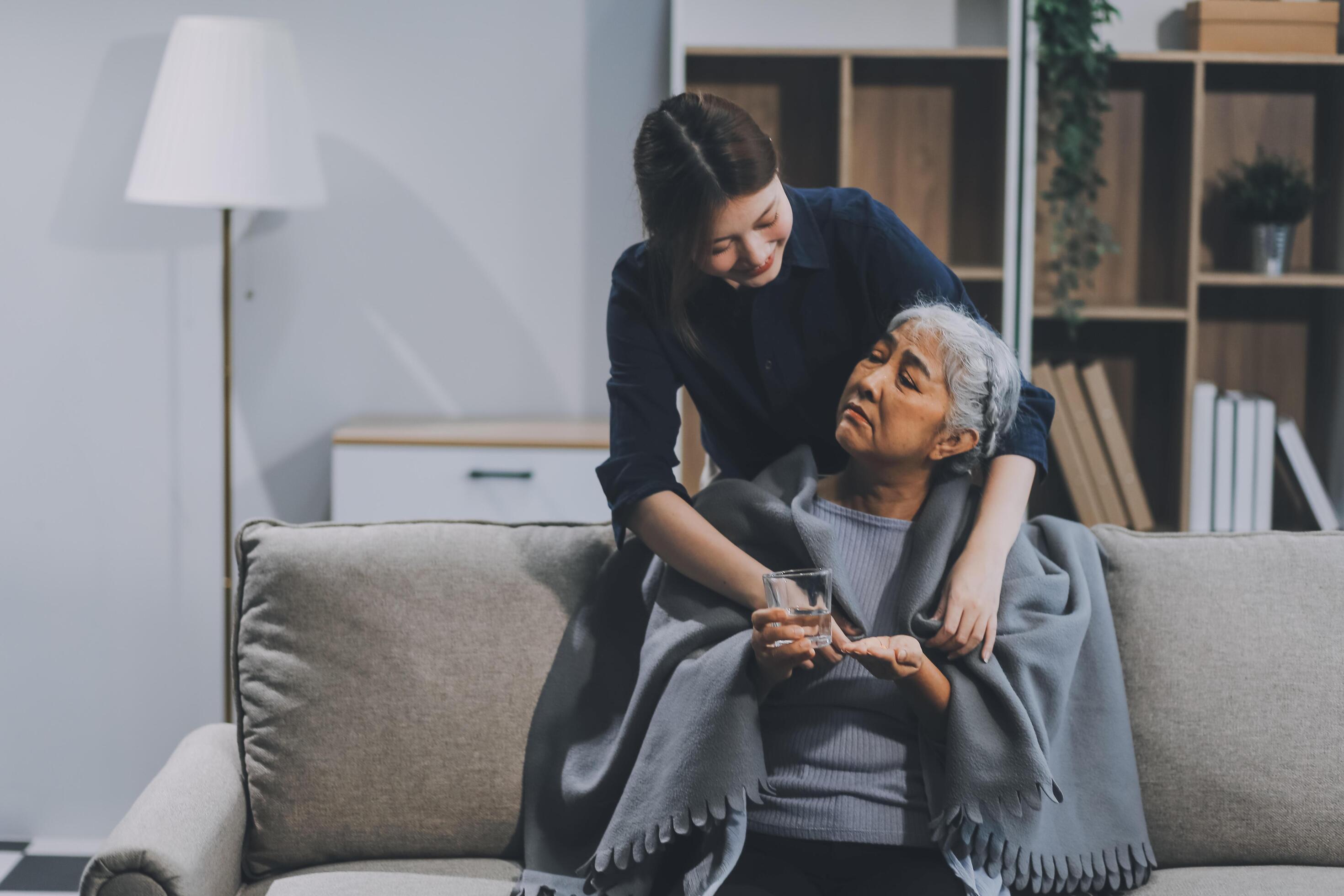 happy family Granddaughter takes care of her grandmother with warm cloths sitting on the sofa. Stock Free