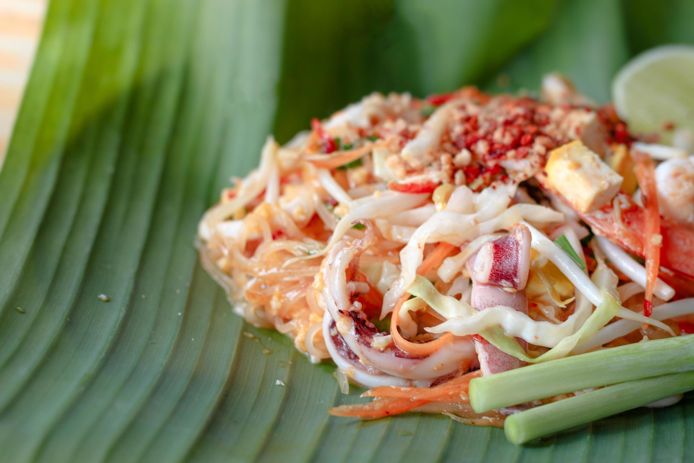 Delicious seafood Pad Thai stir-fried rice noodle on green banana leaf, one of the most popular favorite Thai street food. Stock Free