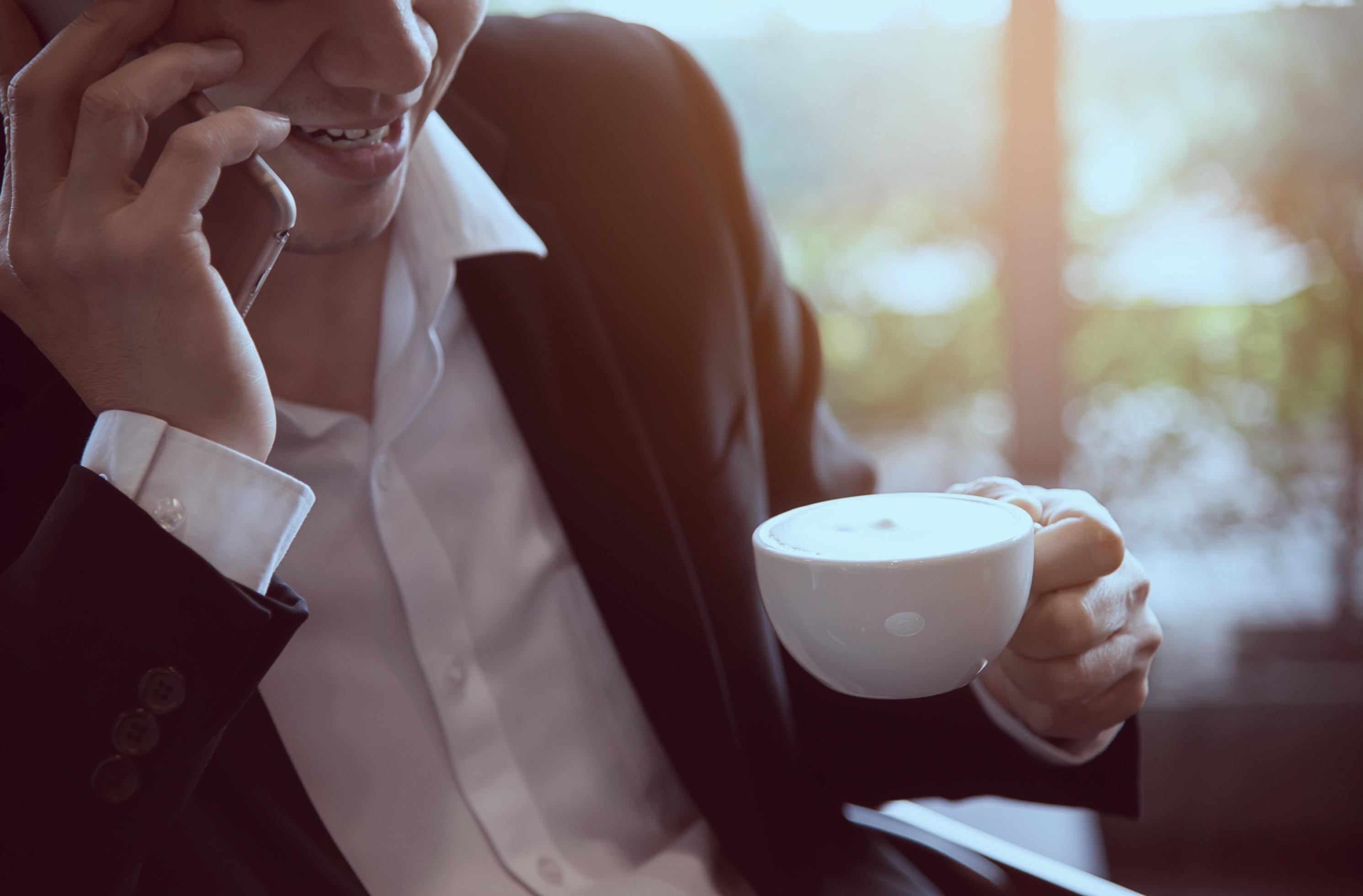 Business man using mobile phone while drinking coffee in coffee shop – modern life style business man in coffee shop concept Stock Free