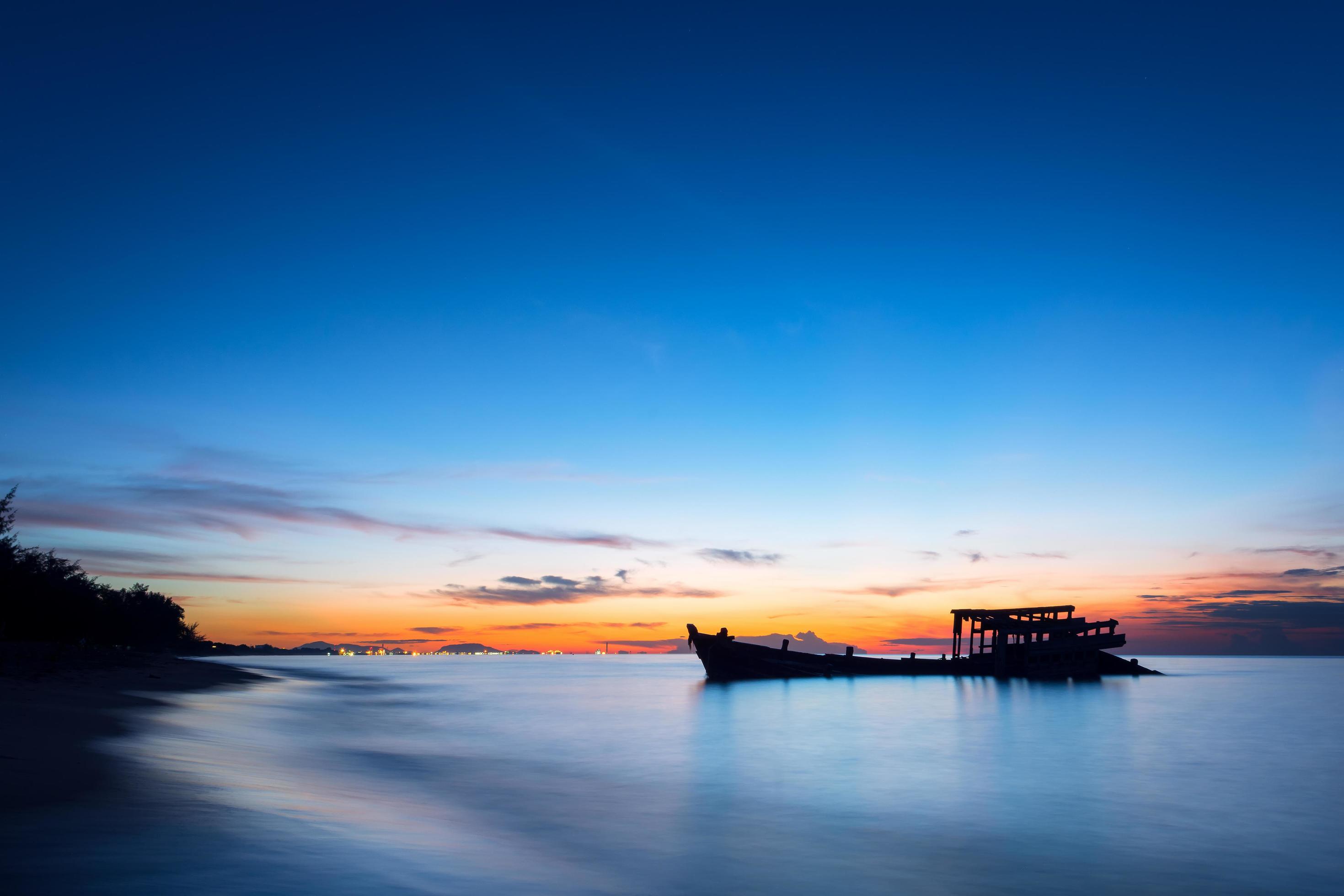 An image of a wrecked fishing boat by the sea at sunset. Stock Free