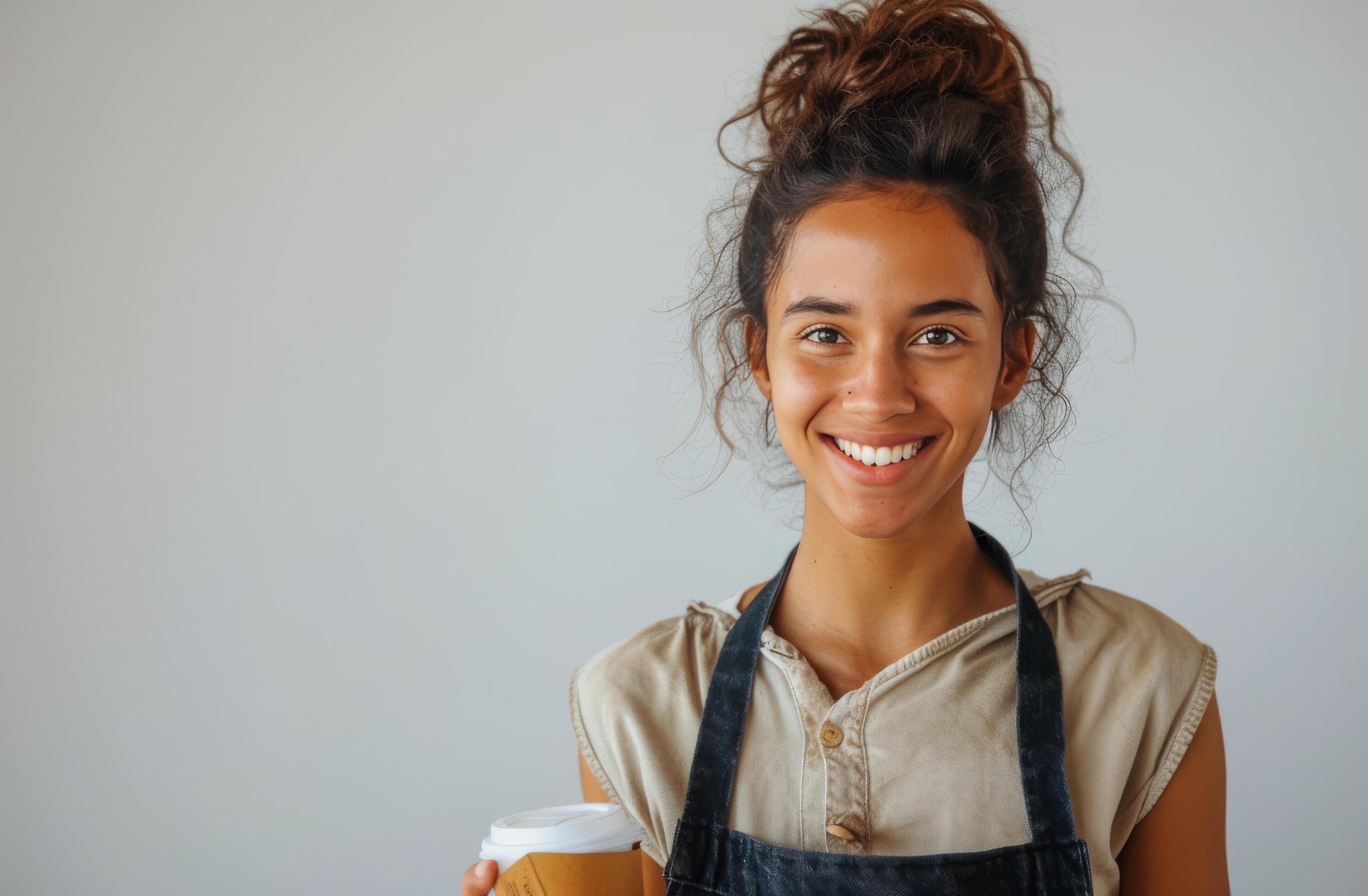 Smiling Woman Holding a Coffee Cup in a White Shirt and Black Apron Stock Free