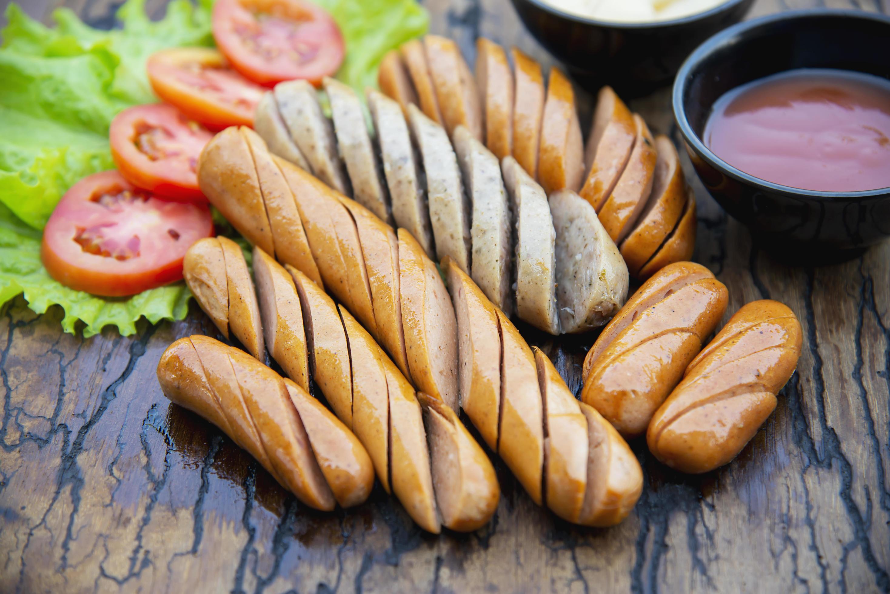 Fried sausages recipe with fresh tomato and sauces ketchup ready to be served, international food style concept Stock Free