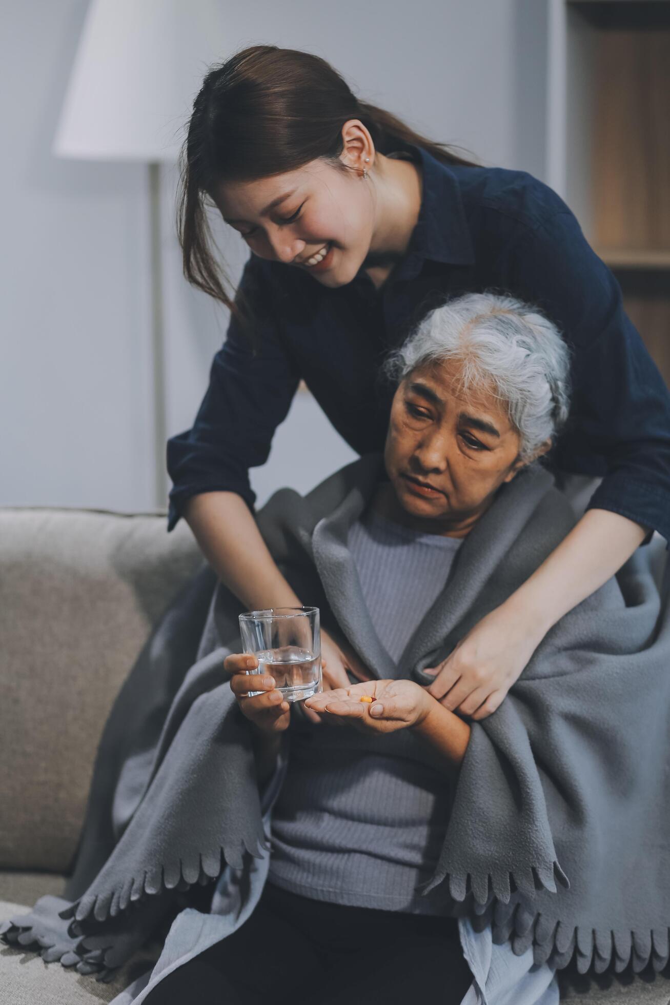 happy family Granddaughter takes care of her grandmother with warm cloths sitting on the sofa. Stock Free