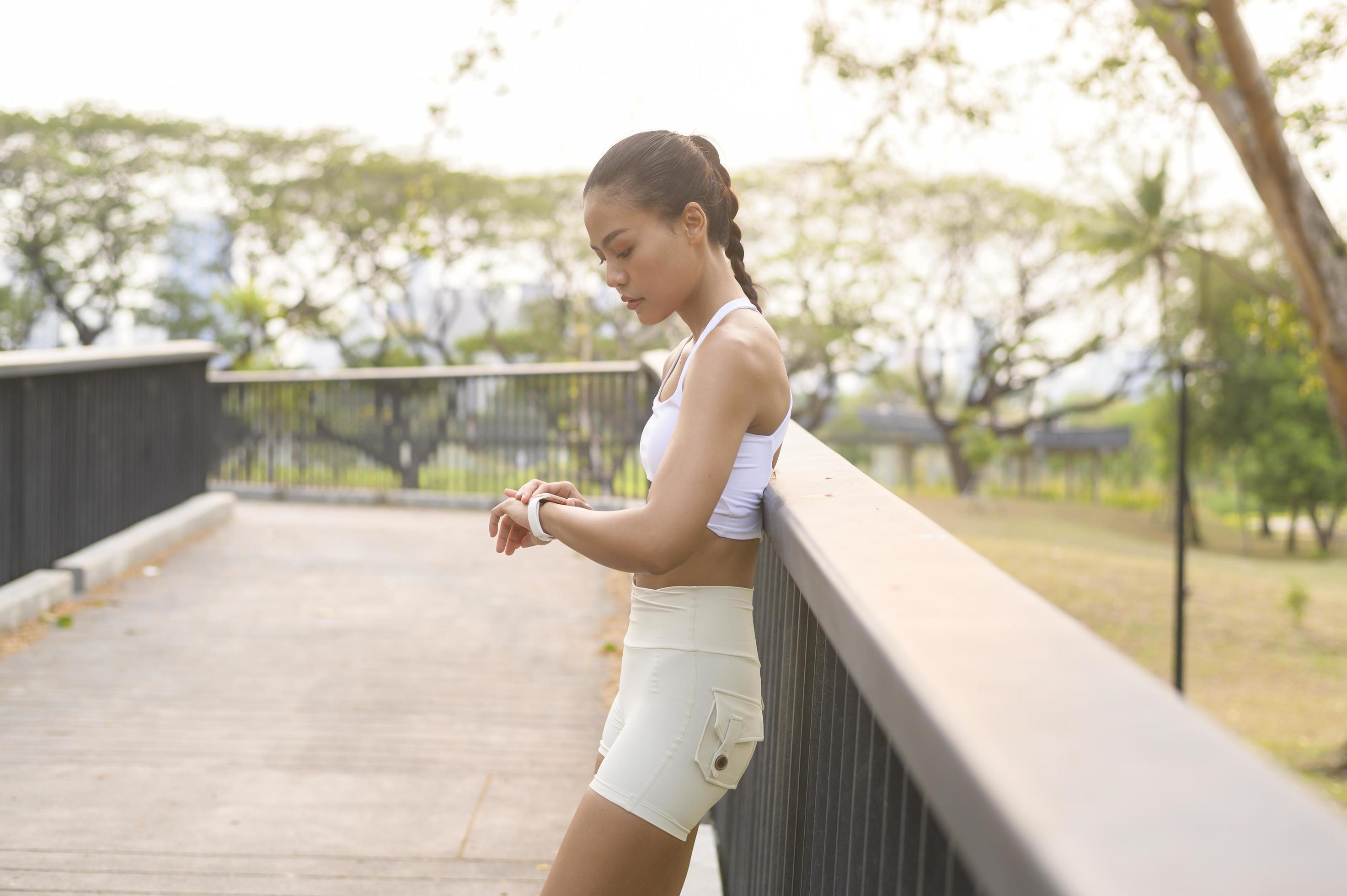 A young fitness woman in sportswear using smart watch while exercising in city park, Healthy and Lifestyles. Stock Free