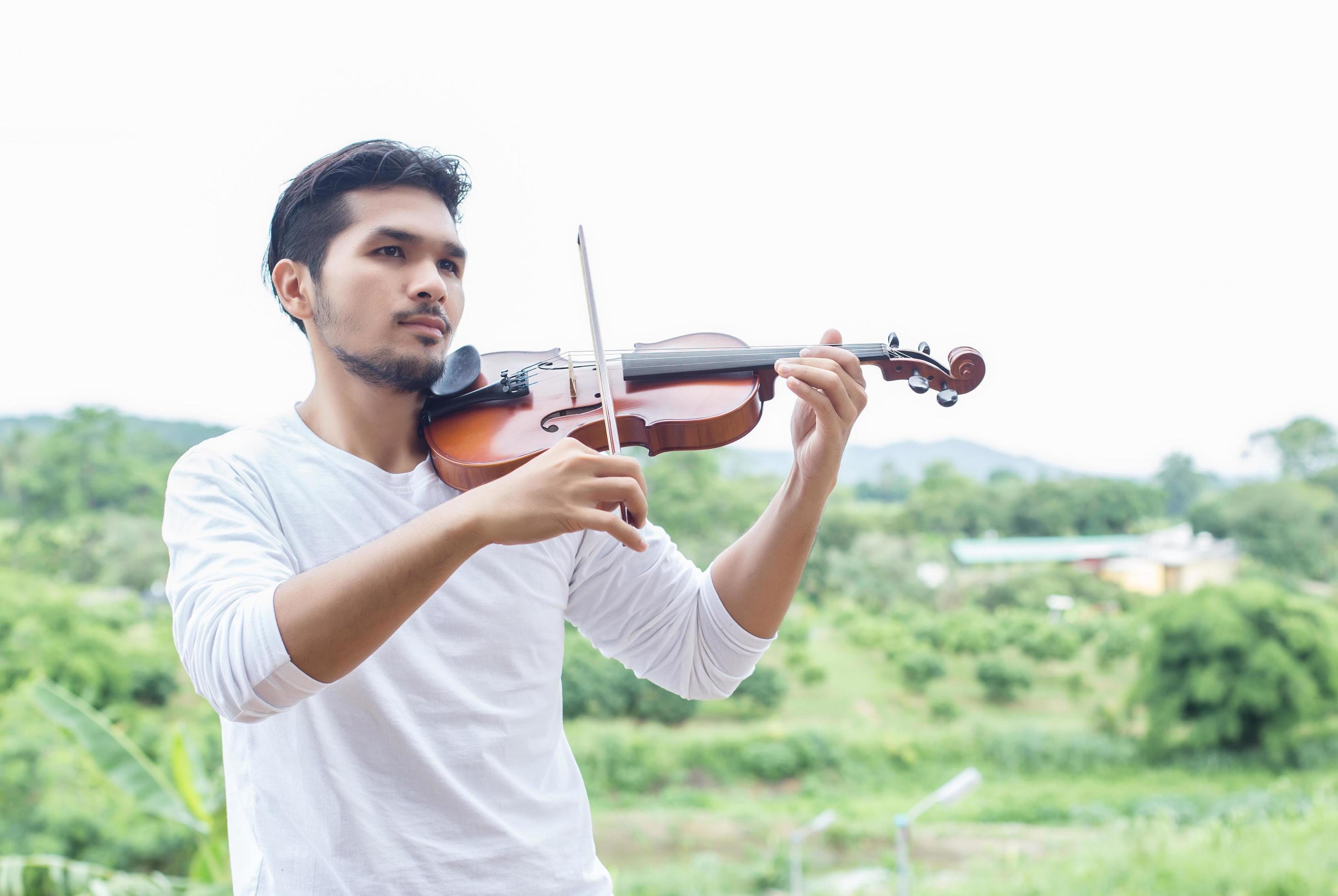 Young hipster musician man playing violin in the nature outdoor lifestyle behind mountain. Stock Free