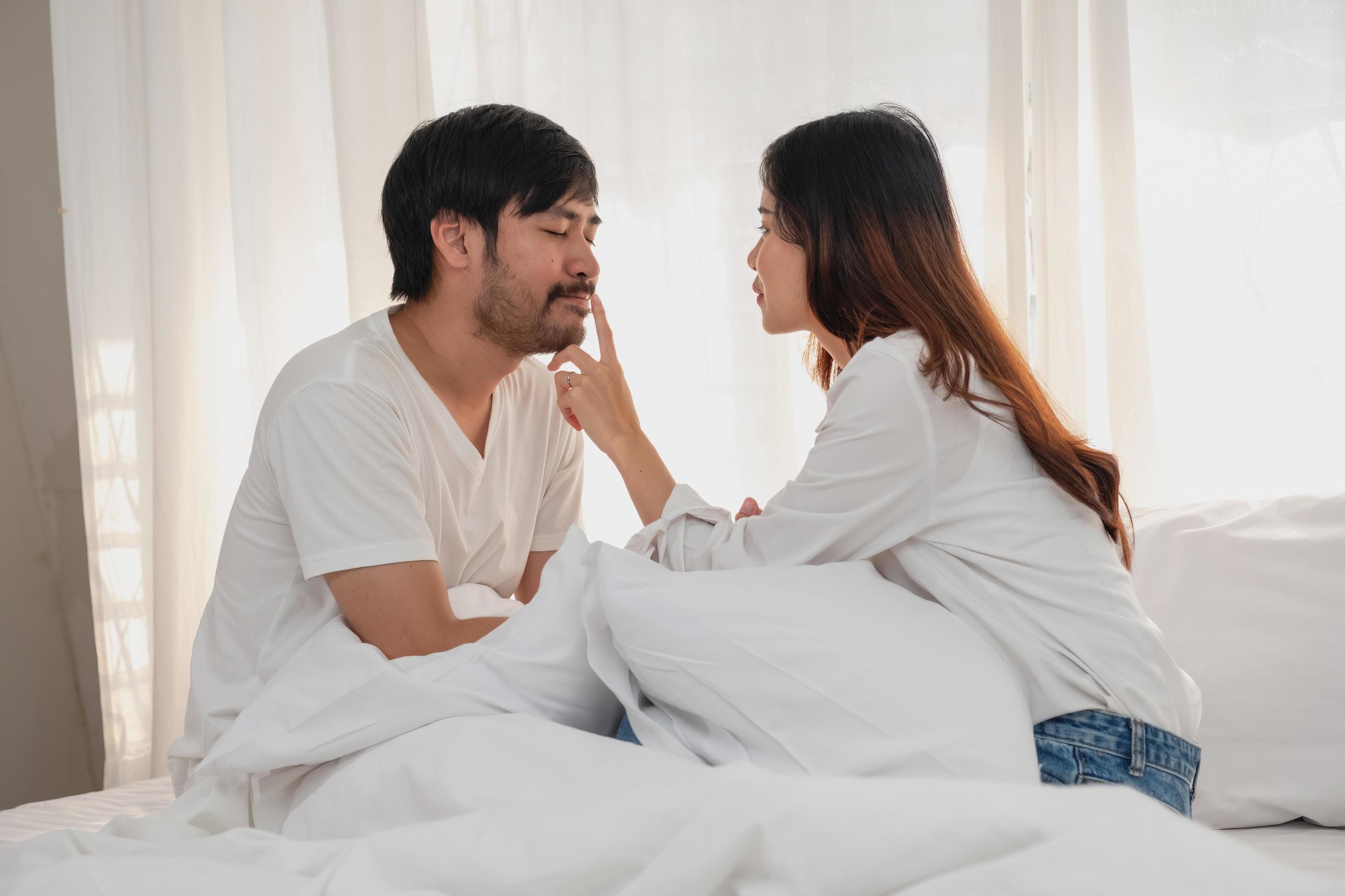 Happy young asian couple embracing, teasing, playing cheerfully in bed at home, romantic time to enhance family bonding. family concept. Stock Free