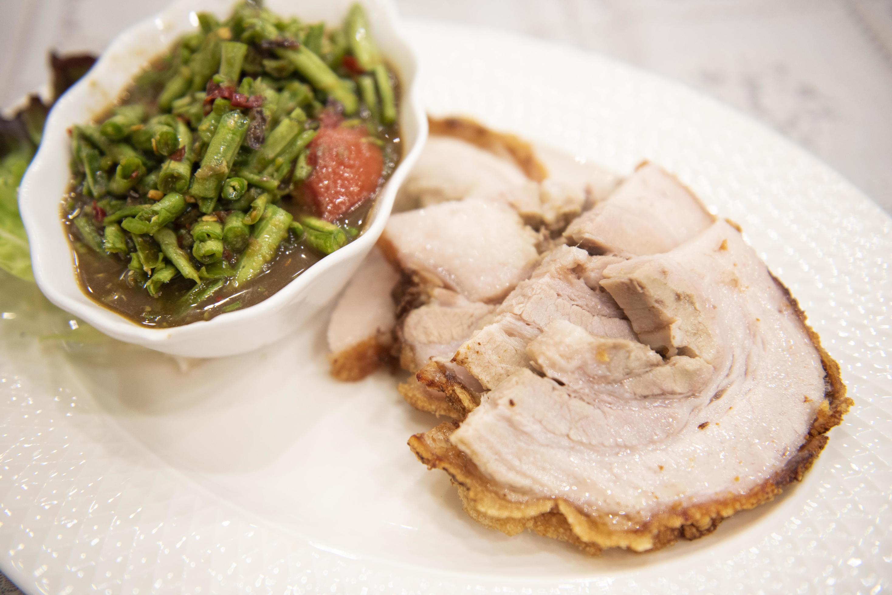 Spicy salad long bean and crispy pork sliced on white plate and vegetable Thai food , Crispy Pork Bean Salad Stock Free