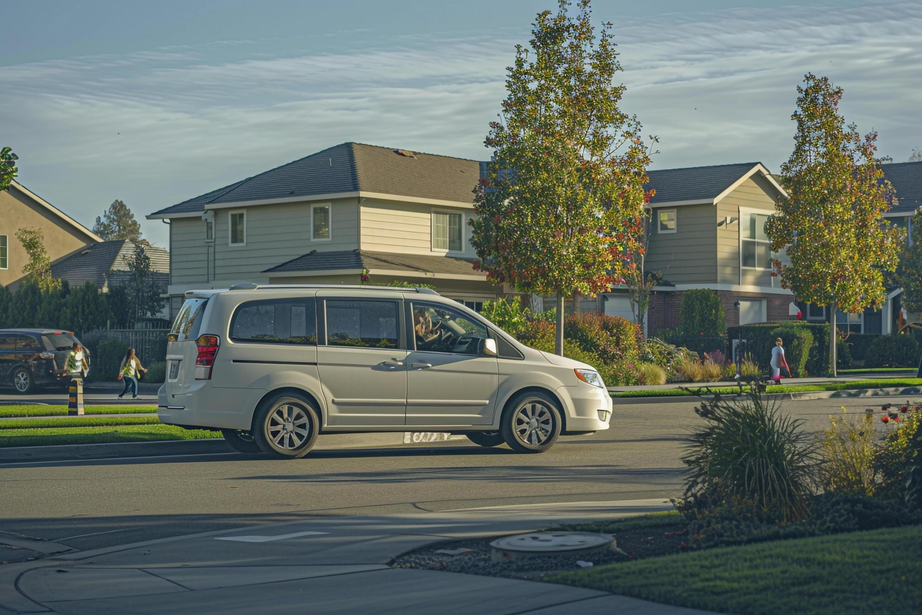 Safety Family minivan driving through residential neighborhood with speed bumps and children playing on sidewalks Stock Free