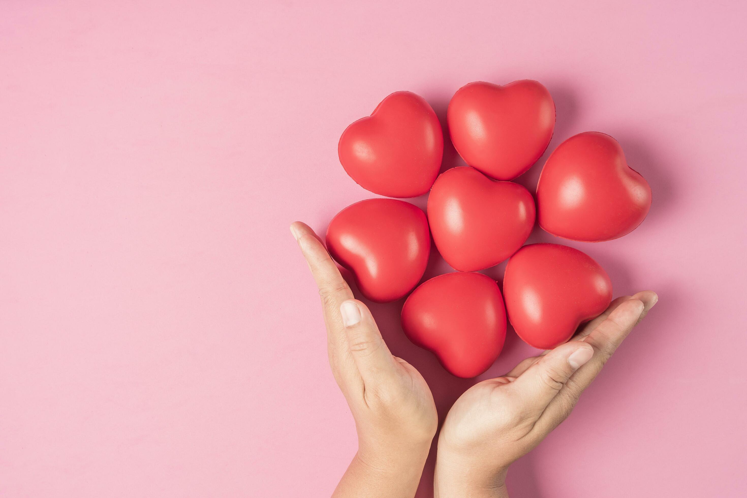 Adult hands around red heart on pink background , health care, organ donation, family life insurance, world heart day, world health day, praying concept Stock Free